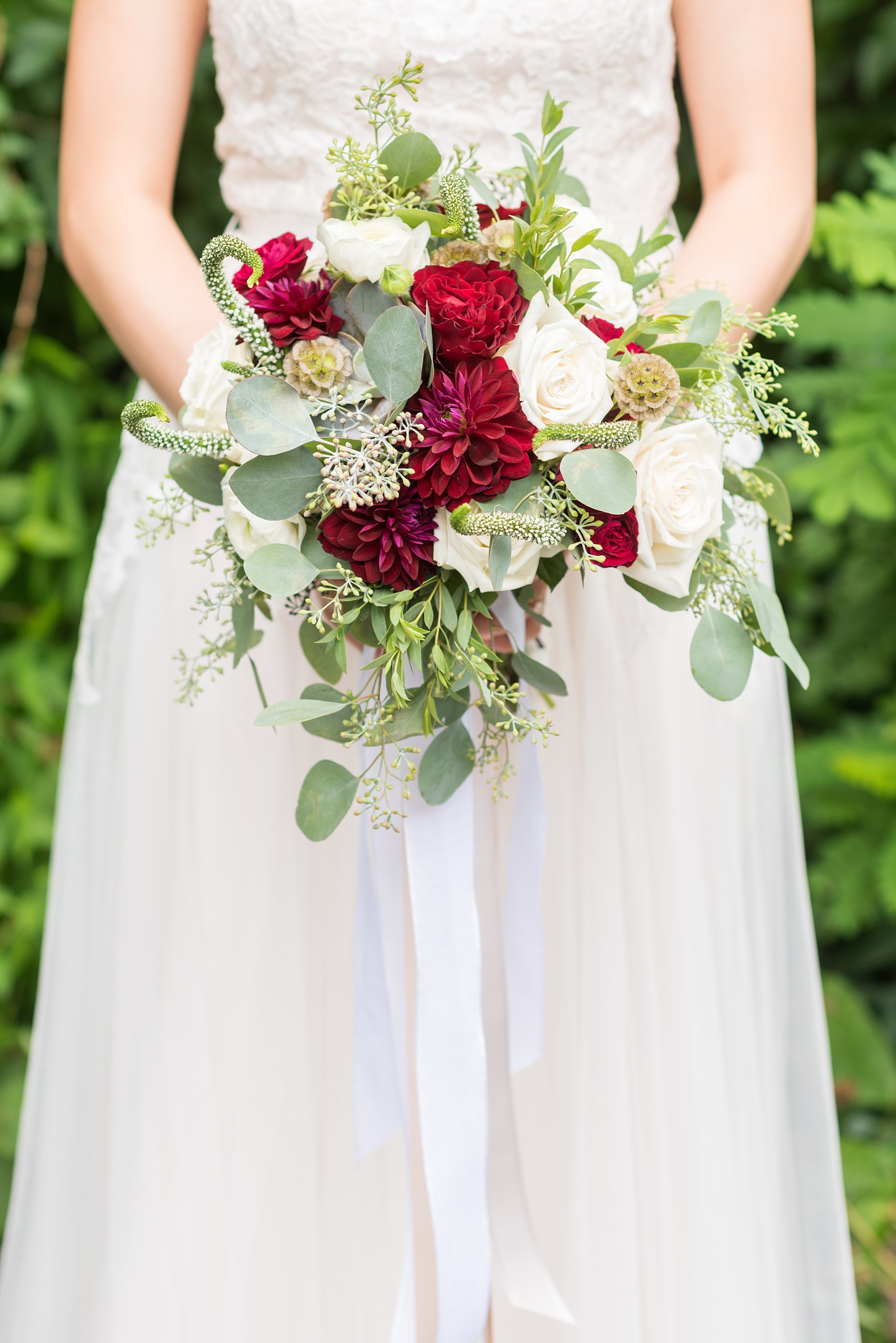 Wedding photos at Crabtree's Kittle House in Chappaqua, New York by Mikkel Paige Photography. The bride held a bouquet with red and white flowers and long neutral colored ribbons at this historic Westchester County venue very close to NYC. Click through to see exactly what flowers were in it! #mikkelpaige #CrabtreesKittleHouse #WestchesterWeddingVenues #WestchesterWedding #summerwedding #weddingdetails #weddingdetails #summerweddingdress #redandwhitebouquet