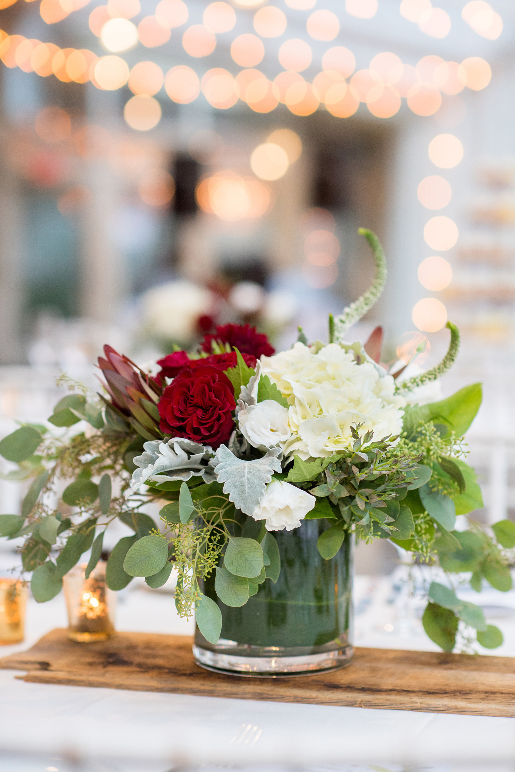 Wedding photos at Crabtree's Kittle House in Chappaqua, New York by Mikkel Paige Photography. The indoor reception was in a historic home, close to NYC in Westchester county. The red and white floral centerpieces were placed under twinkle market lights. Click through for more reception inspiration from this beautiful summer wedding! #mikkelpaige #CrabtreesKittleHouse #WestchesterWeddingVenues #WestchesterWedding #summerwedding #redandwhiteflowercenterpieces #redandwhiteflowers #marketlights