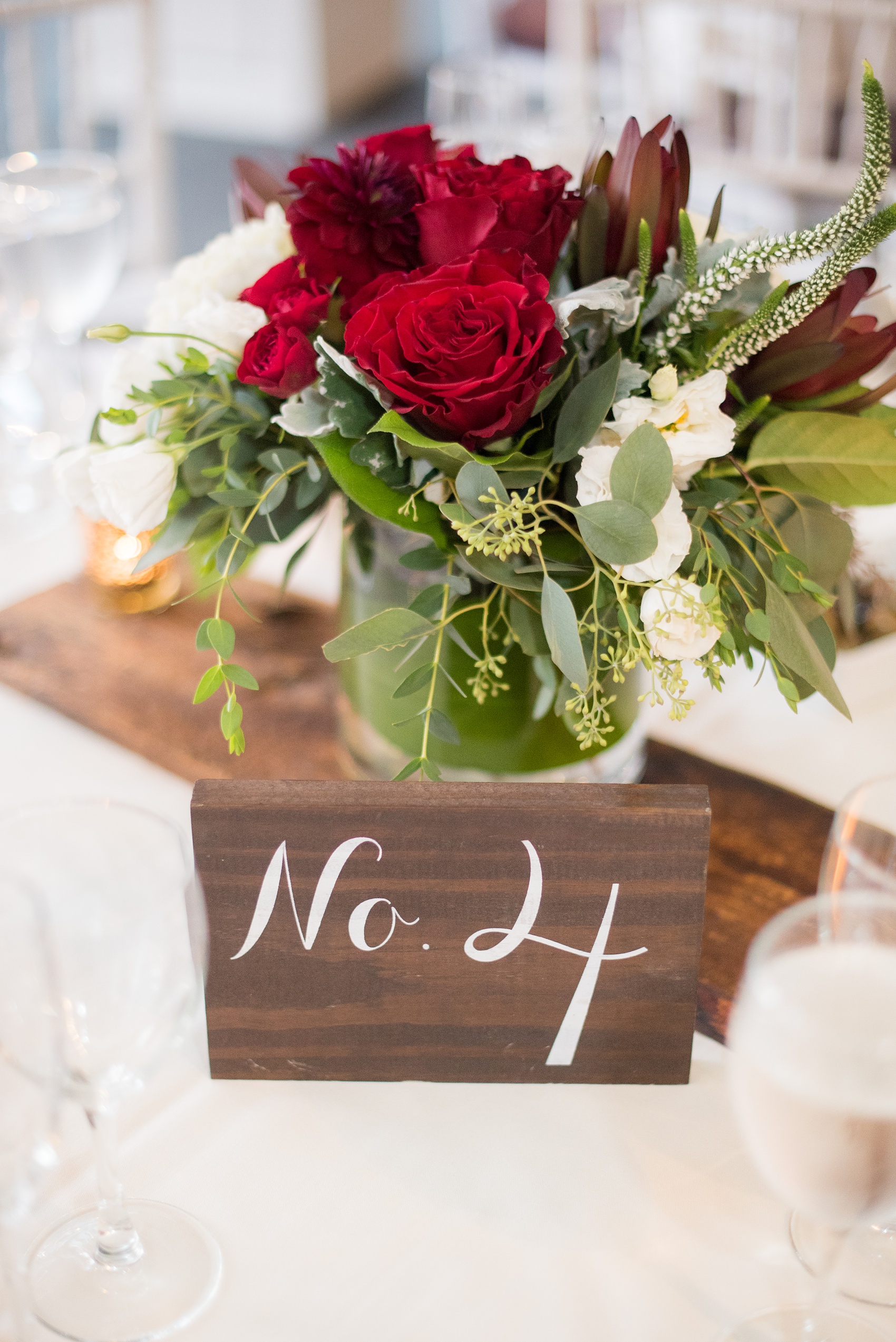 Wedding photos at Crabtree's Kittle House in Chappaqua, New York by Mikkel Paige Photography. The indoor reception was in a historic home close to NYC in Westchester county. The tables had custom wood boards with white calligraphy table numbers on them. Click through for more reception details inspiration from this summer wedding! #mikkelpaige #CrabtreesKittleHouse #WestchesterWeddingVenues #WestchesterWedding #summerwedding #receptiondetails #woodentablenumbers #tablenumbers #redandwhitecenterpieces