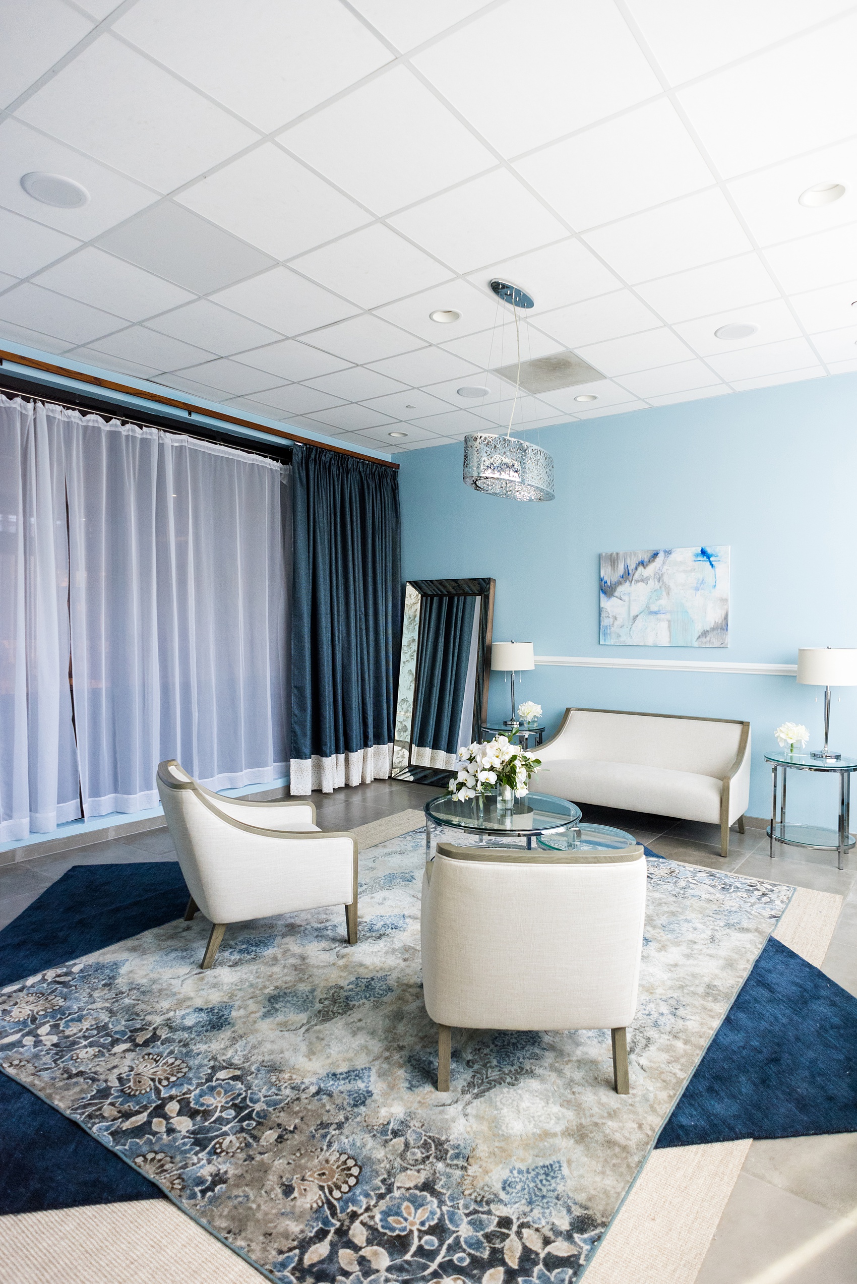 Downtown Raleigh wedding venue photos of Vidrio on Glenwood South, and their beautiful new bridal suite. Blue hues and neutral furniture are framed by paintings and a full length mirror in this beautiful space. #MikkelPaige #Vidrio #DowntownRaleigh #RalegihWeddingVenues