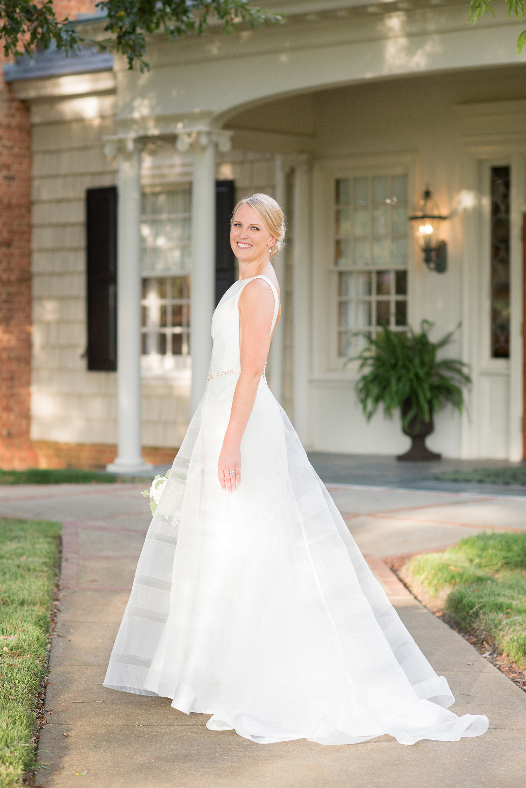 Pictures by Mikkel Paige Photography of a wedding in Durham, North Carolina. The bride carried hydrangea flowers for the garden-like golf course photos with her groom, and had a tulle overlay for the ceremony. Her low-back gown and up-do hair twists were beautiful! Click through to the website post for complete details and more inspiration! #durhamNC #northcarolinawedding #golfcoursewedding #CountryClub #DurhamWedding #summerwedding #weddinggown #lowbackweddinggown #tulleweddingdress