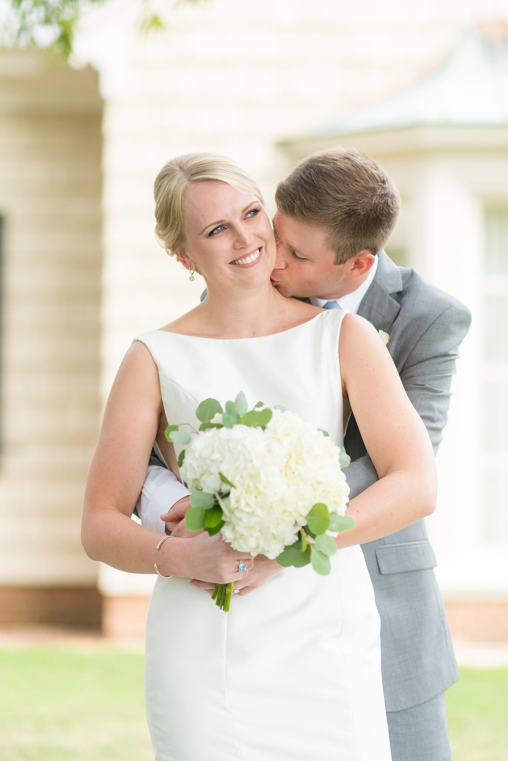 Pictures by Mikkel Paige Photography of a wedding in Durham, North Carolina. The bride carried hydrangea flowers for the garden-like golf course photos with her groom, who wore a grey suit. Her low-back gown and up-do hair twists were beautiful! Click through to the website post for complete details and more inspiration! #durhamNC #northcarolinawedding #golfcoursewedding #CountryClub #DurhamWedding #summerwedding #weddinggown #lowbackweddinggown #brideandgroom