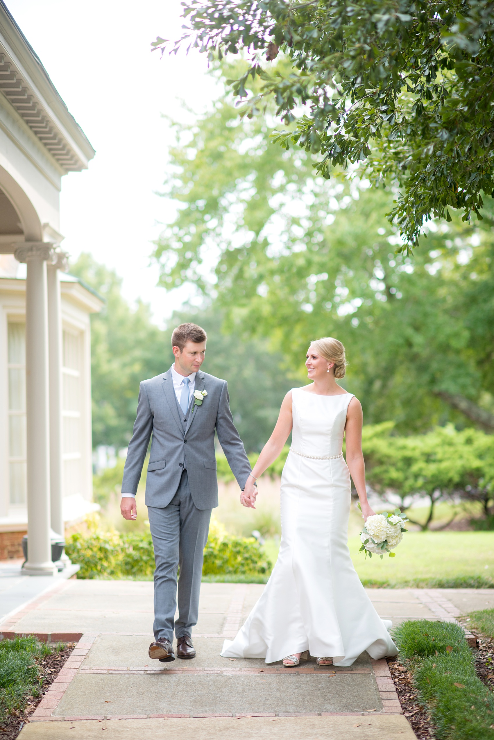 Pictures by Mikkel Paige Photography of a wedding in Durham, North Carolina. The bride carried hydrangea flowers for the garden-like golf course photos with her groom, who wore a grey suit. Her low-back gown and up-do hair twists were beautiful! Click through to the website post for complete details and more inspiration! #durhamNC #northcarolinawedding #golfcoursewedding #CountryClub #DurhamWedding #summerwedding #weddinggown #lowbackweddinggown #brideandgroom