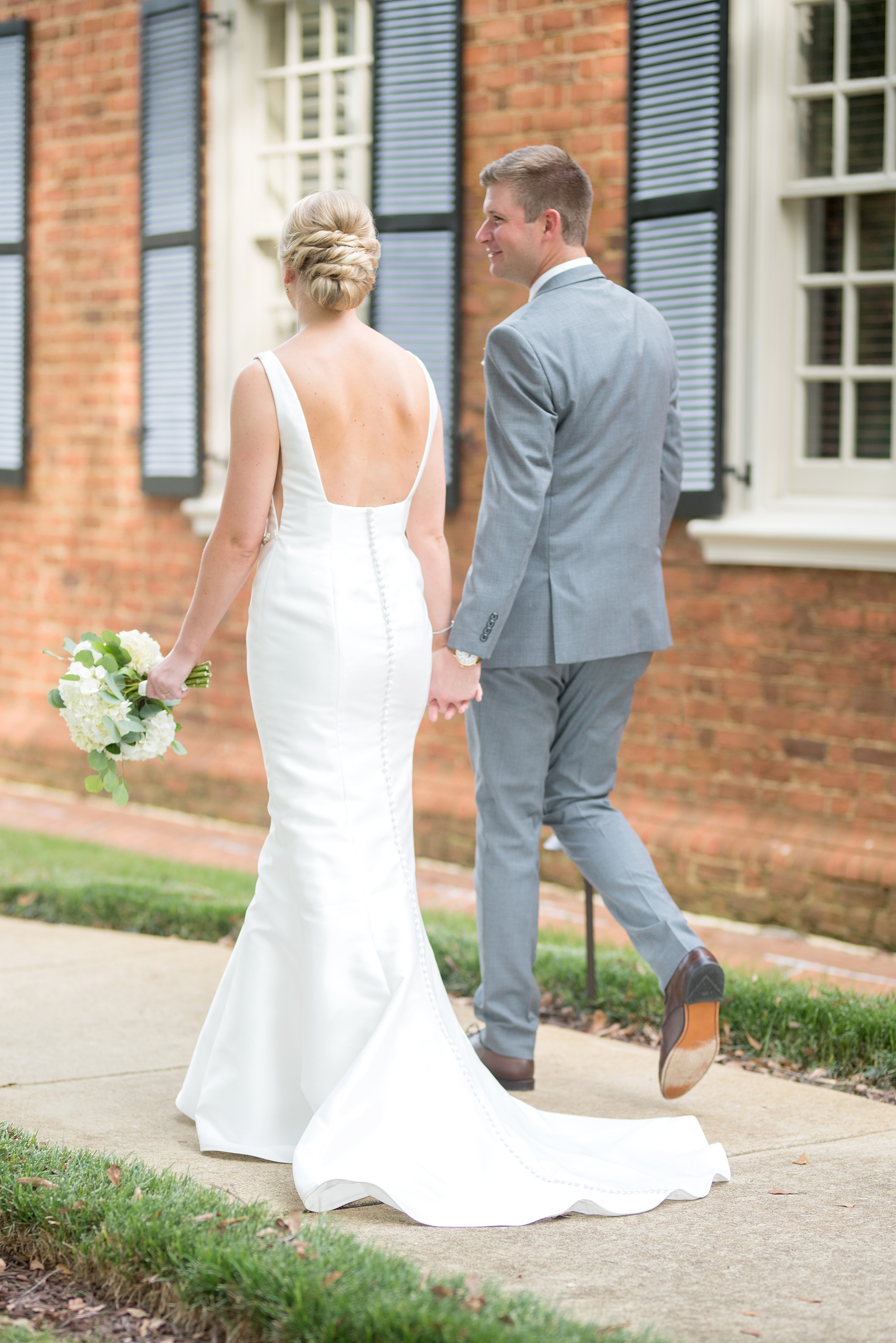 Pictures by Mikkel Paige Photography of a wedding in Durham, North Carolina. The bride carried hydrangea flowers for the garden-like golf course photos with her groom, who wore a grey suit. Her low-back gown and up-do hair twists were beautiful! Click through to the website post for complete details and more inspiration! #durhamNC #northcarolinawedding #golfcoursewedding #CountryClub #DurhamWedding #summerwedding #weddinggown #lowbackweddinggown #brideandgroom