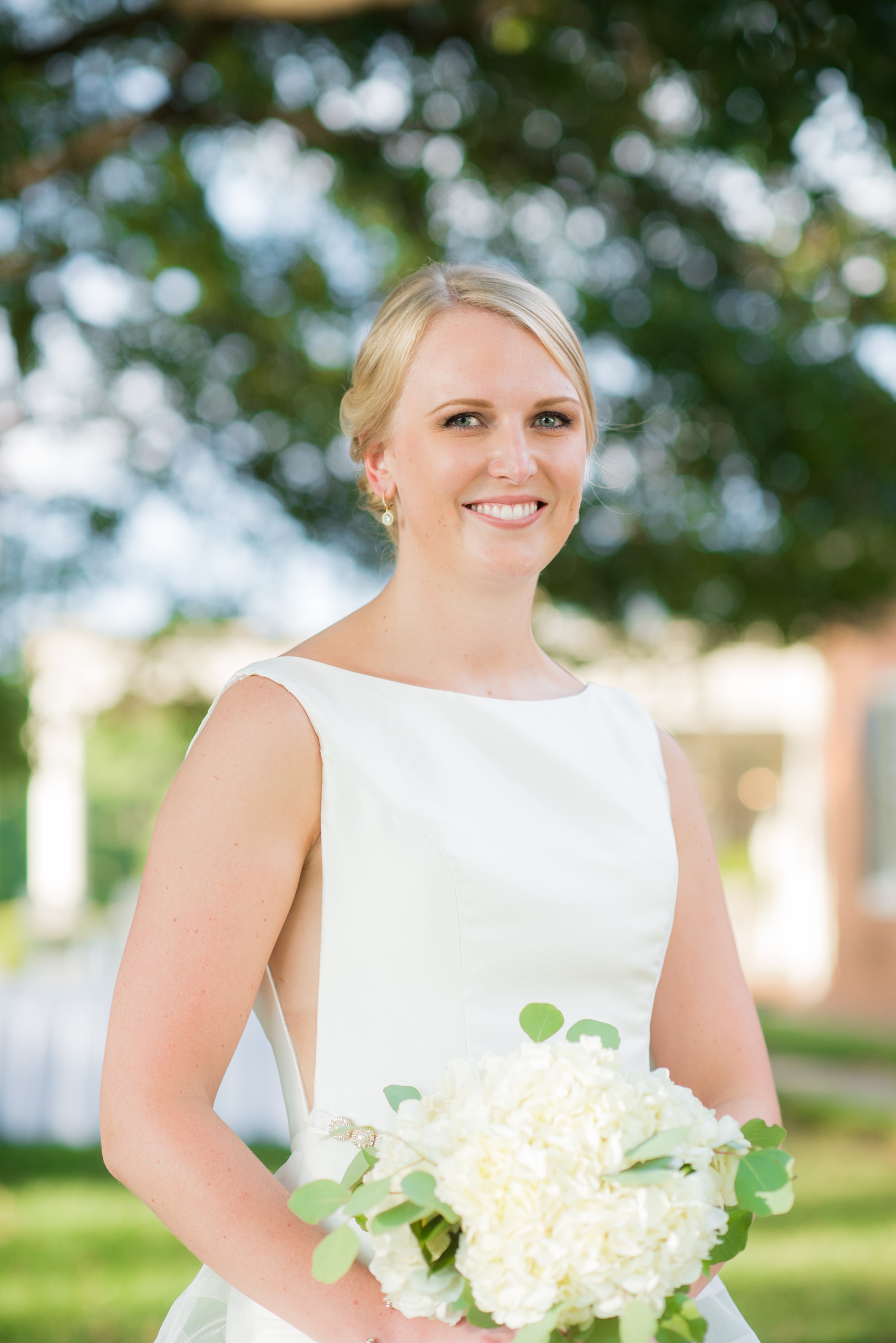 Pictures by Mikkel Paige Photography of a wedding in Durham, North Carolina. The bride carried hydrangea flowers for the garden-like golf course photos with her groom, who wore a grey suit. Her low-back gown and up-do hair twists were beautiful! Click through to the website post for complete details and more inspiration! #durhamNC #northcarolinawedding #golfcoursewedding #CountryClub #DurhamWedding #summerwedding #weddinggown #lowbackweddinggown #brideandgroom