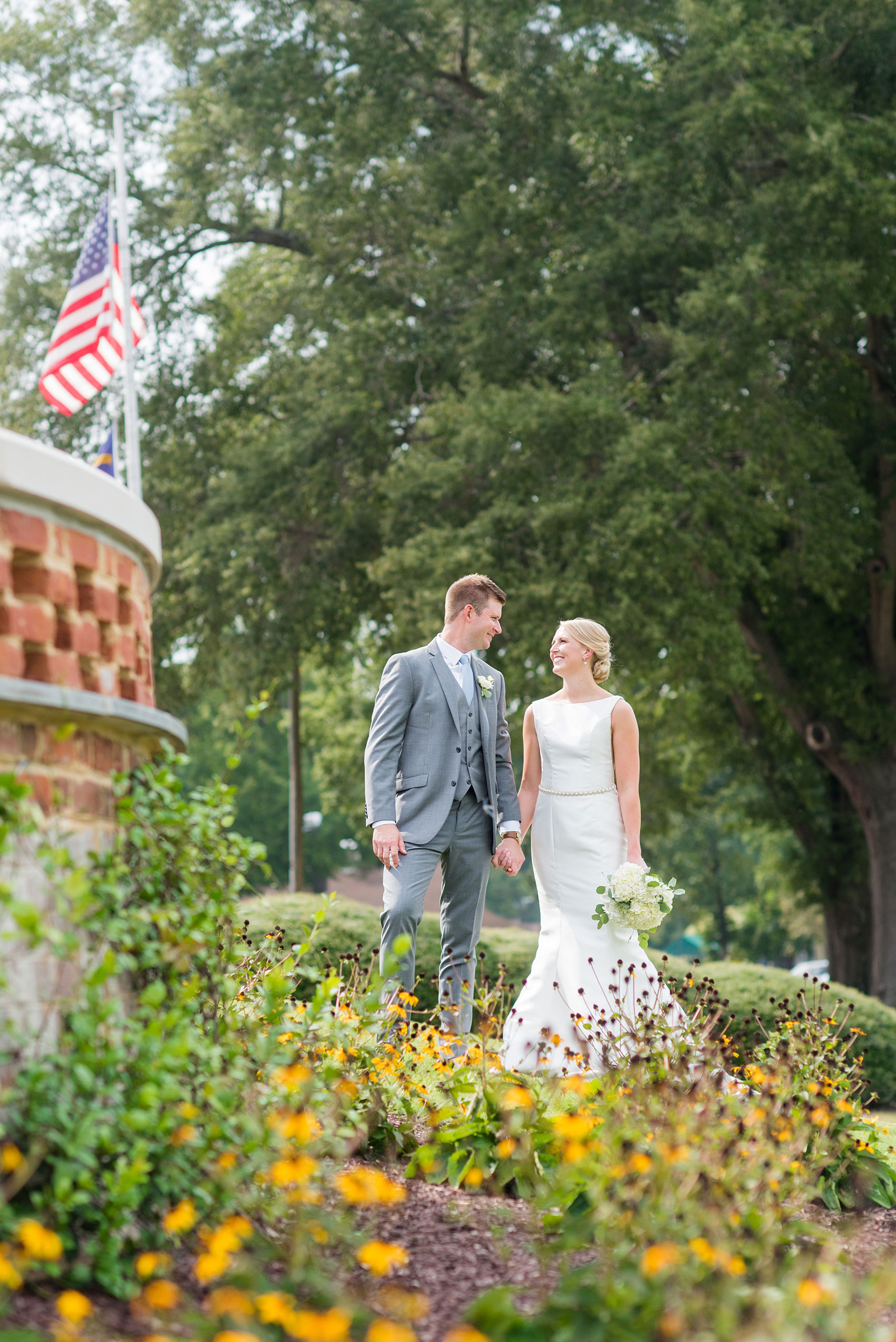 Pictures by Mikkel Paige Photography of a wedding in Durham, North Carolina. The bride carried hydrangea flowers for the garden-like golf course photos with her groom, who wore a grey suit. Her low-back gown and up-do hair twists were beautiful! Click through to the website post for complete details and more inspiration! #durhamNC #northcarolinawedding #golfcoursewedding #CountryClub #DurhamWedding #summerwedding #weddinggown #lowbackweddinggown #brideandgroom