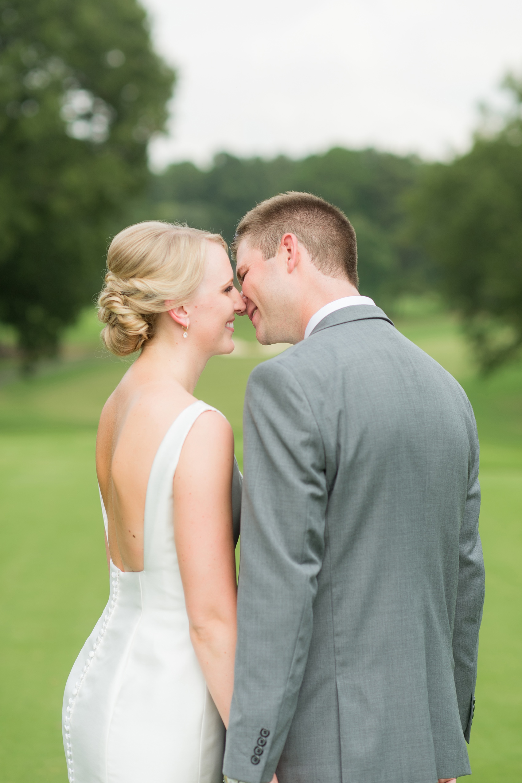 Pictures by Mikkel Paige Photography of a wedding in Durham, North Carolina. The bride carried hydrangea flowers for the garden-like golf course photos with her groom, who wore a grey suit. Her low-back gown and up-do hair twists were beautiful! Click through to the website post for complete details and more inspiration! #durhamNC #northcarolinawedding #golfcoursewedding #CountryClub #DurhamWedding #summerwedding #weddinggown #lowbackweddinggown #brideandgroom