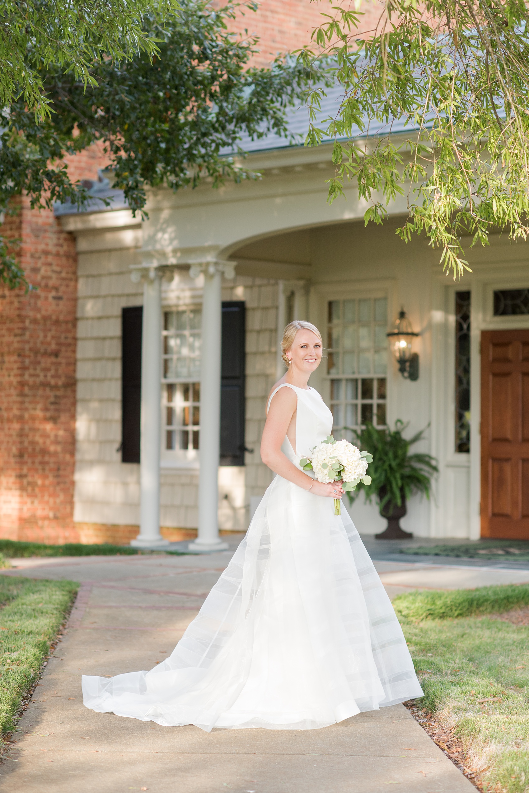 Pictures by Mikkel Paige Photography of a wedding in Durham, North Carolina. The bride carried hydrangea flowers for the garden-like golf course photos with her groom, who wore a grey suit. Her low-back gown and up-do hair twists were beautiful! Click through to the website post for complete details and more inspiration! #durhamNC #northcarolinawedding #golfcoursewedding #CountryClub #DurhamWedding #summerwedding #weddinggown #lowbackweddinggown #brideandgroom