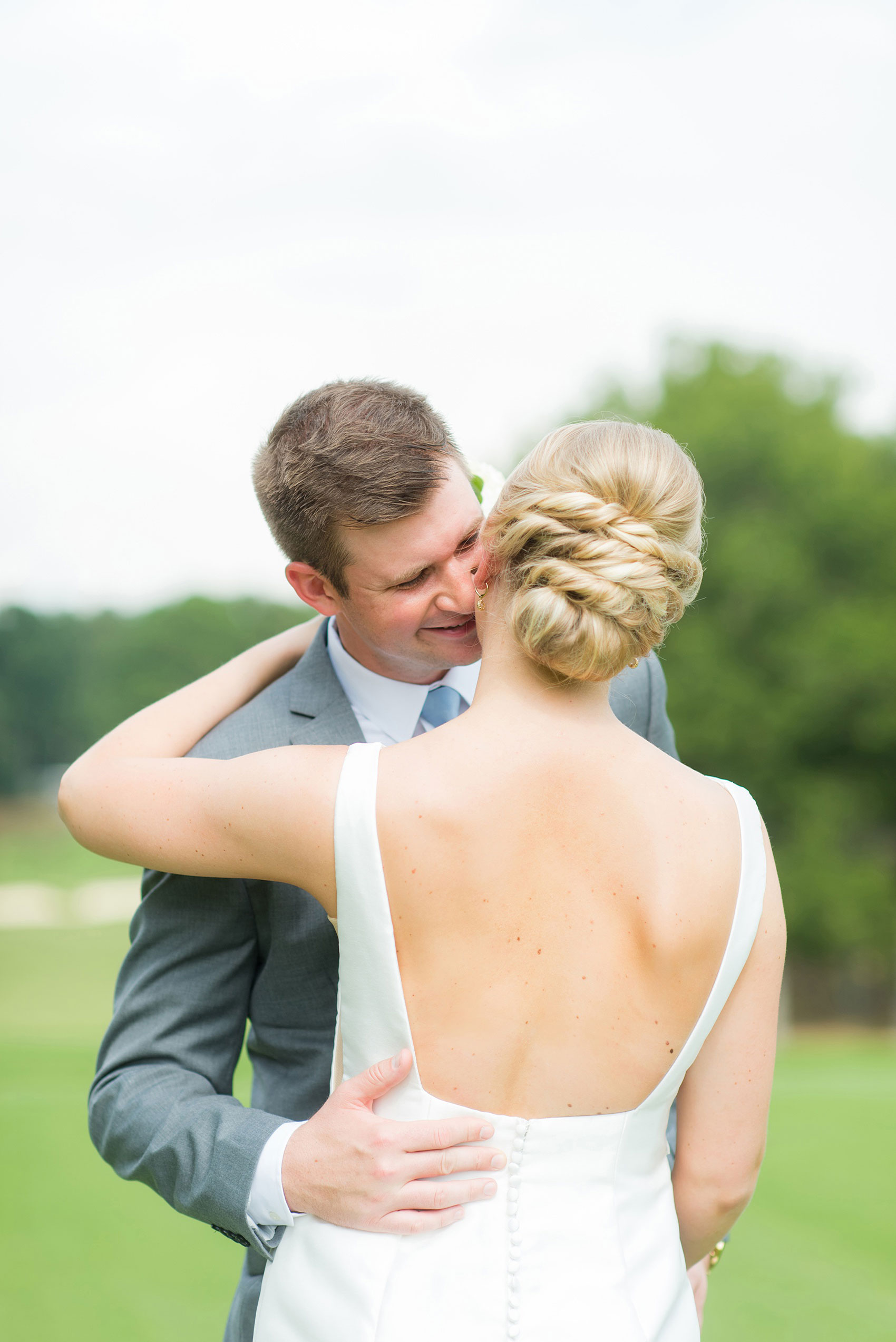 Pictures by Mikkel Paige Photography of a wedding in Durham, North Carolina. The bride carried hydrangea flowers for the garden-like golf course photos with her groom, who wore a grey suit. Her low-back gown and up-do hair twists were beautiful! Click through to the website post for complete details and more inspiration! #durhamNC #northcarolinawedding #golfcoursewedding #CountryClub #DurhamWedding #summerwedding #weddinggown #lowbackweddinggown #brideandgroom