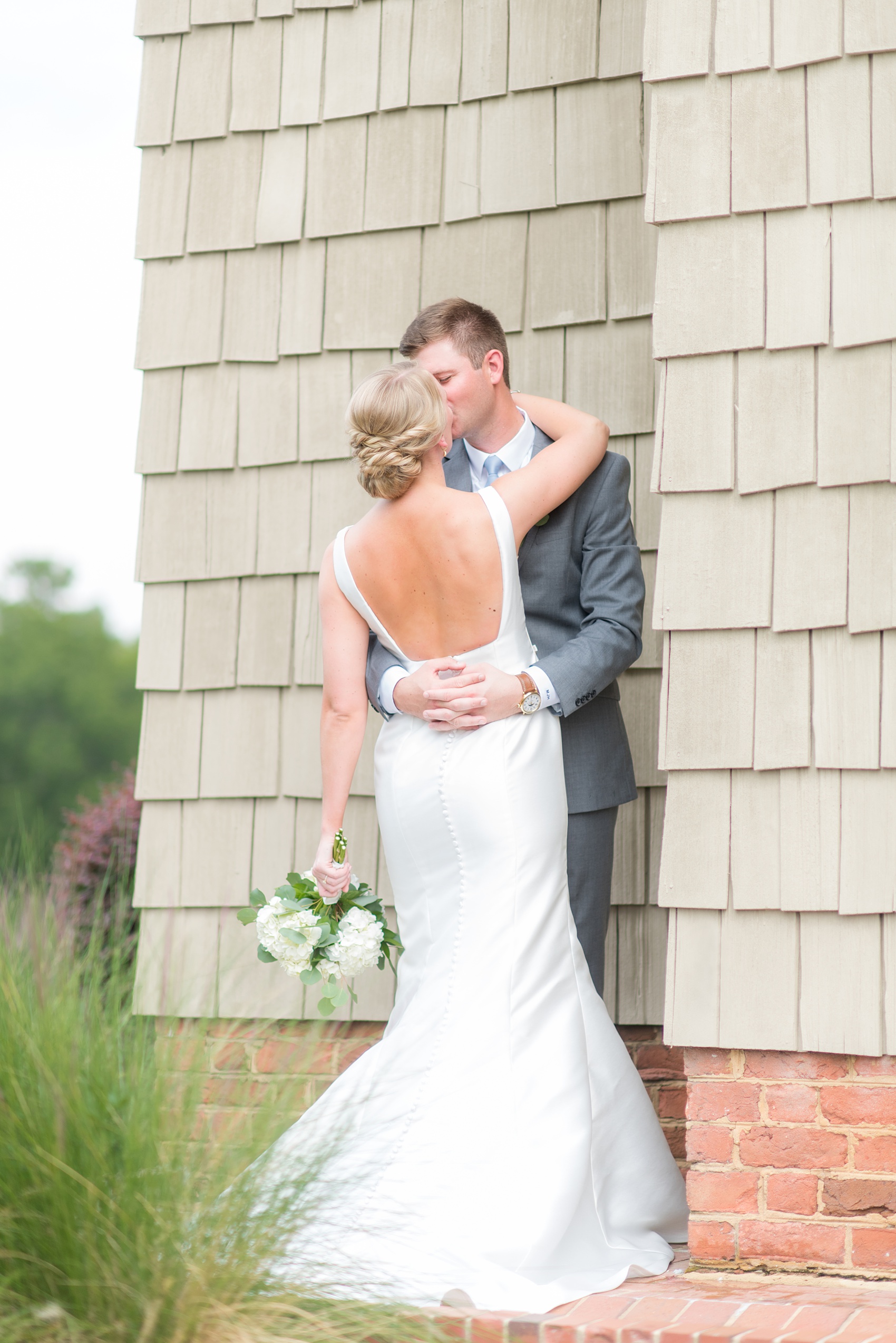 Pictures by Mikkel Paige Photography of a wedding in Durham, North Carolina. The bride carried hydrangea flowers for the garden-like golf course photos with her groom, who wore a grey suit. Her low-back gown and up-do hair twists were beautiful! Click through to the website post for complete details and more inspiration! #durhamNC #northcarolinawedding #golfcoursewedding #CountryClub #DurhamWedding #summerwedding #weddinggown #lowbackweddinggown #brideandgroom #firstlook