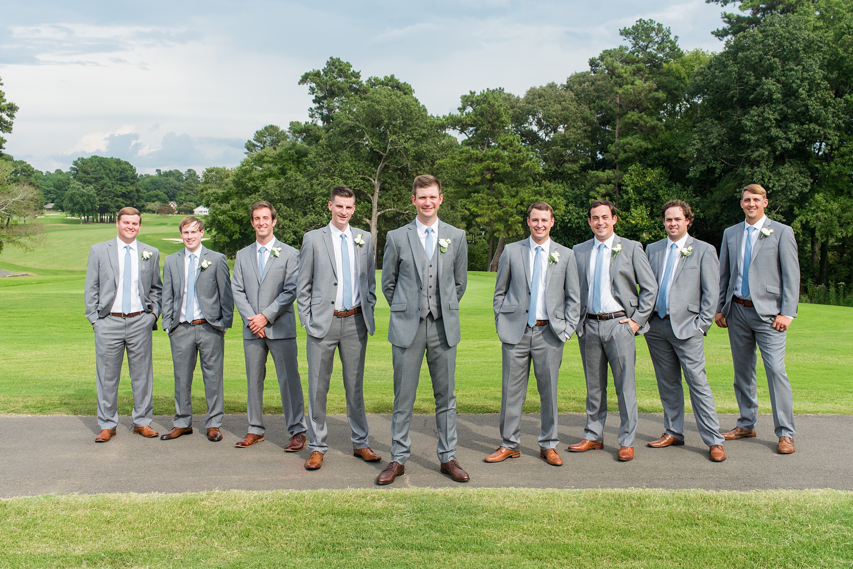Pictures by Mikkel Paige Photography of a wedding in Durham, North Carolina. The groom wore a white rose boutonniere with grey suit and blue tie while for the garden-like golf course photos together. He gifted all his best friends unique socks for a special detail! Click through to the website post for complete inspiration! #durhamNC #northcarolinawedding #golfcoursewedding #CountryClub #DurhamWedding #summerwedding #groom #blueties #groomsmen #greysuits