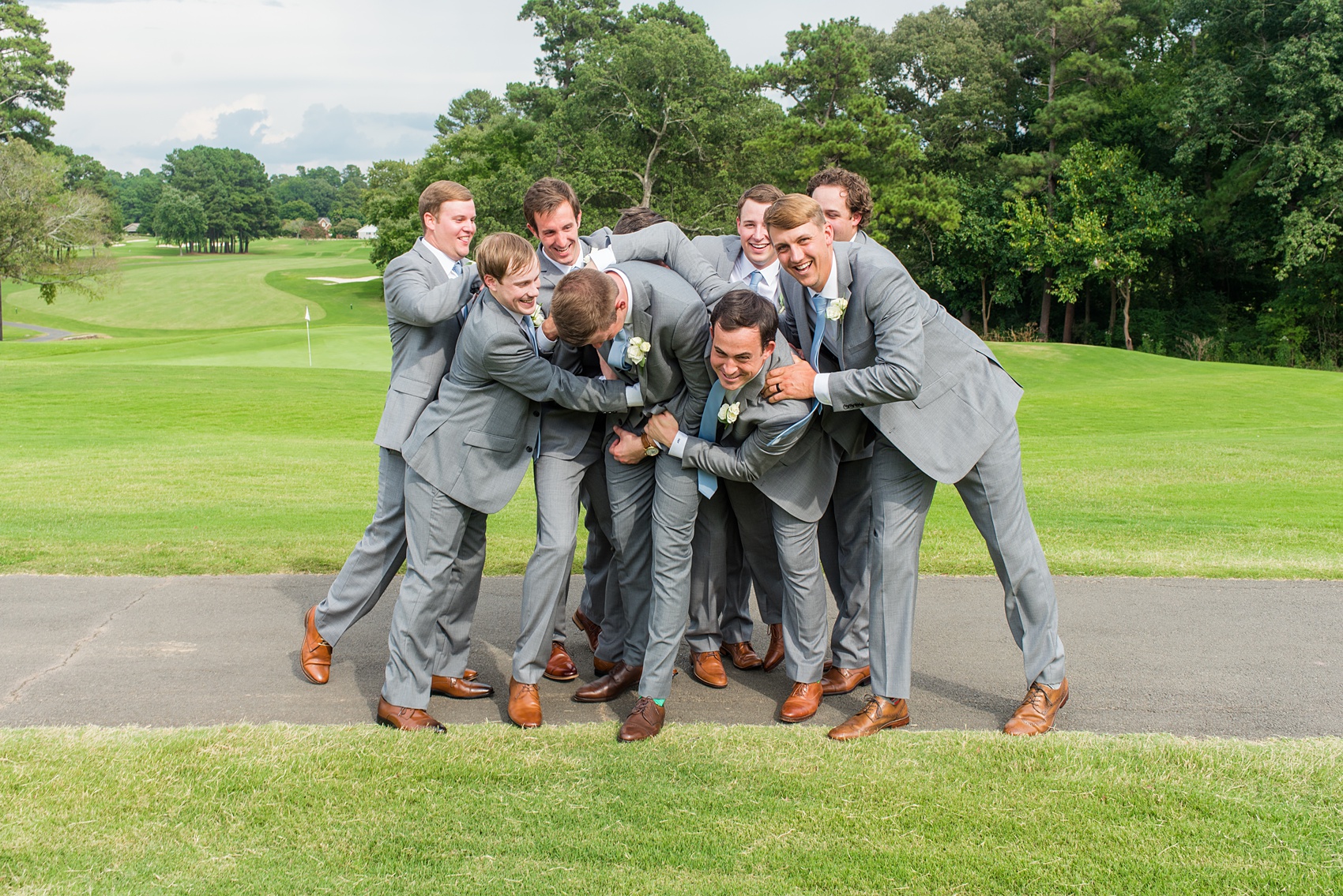 Pictures by Mikkel Paige Photography of a wedding in Durham, North Carolina. The groom wore a white rose boutonniere with grey suit and blue tie while for the garden-like golf course photos together. He gifted all his best friends unique socks for a special detail! Click through to the website post for complete inspiration! #durhamNC #northcarolinawedding #golfcoursewedding #CountryClub #DurhamWedding #summerwedding #groom #blueties #groomsmen #greysuits