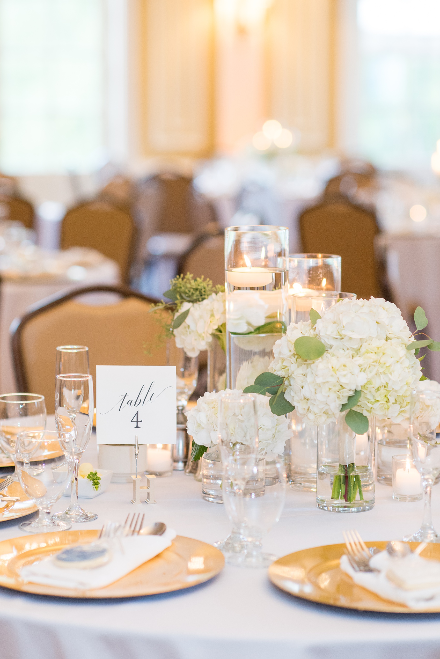 Pictures by Mikkel Paige Photography of a wedding in Durham, North Carolina. The beautiful hydrangea flowers from the day’s events adorned the party room that overlooked a pretty garden-like golf course. Some reception tables had low floral arrangements while others had high ones. Each had a script table number and candles. Click through to our website for the complete post! #durhamNC #northcarolinawedding #golfcoursewedding #CountryClub #DurhamWedding #summerwedding