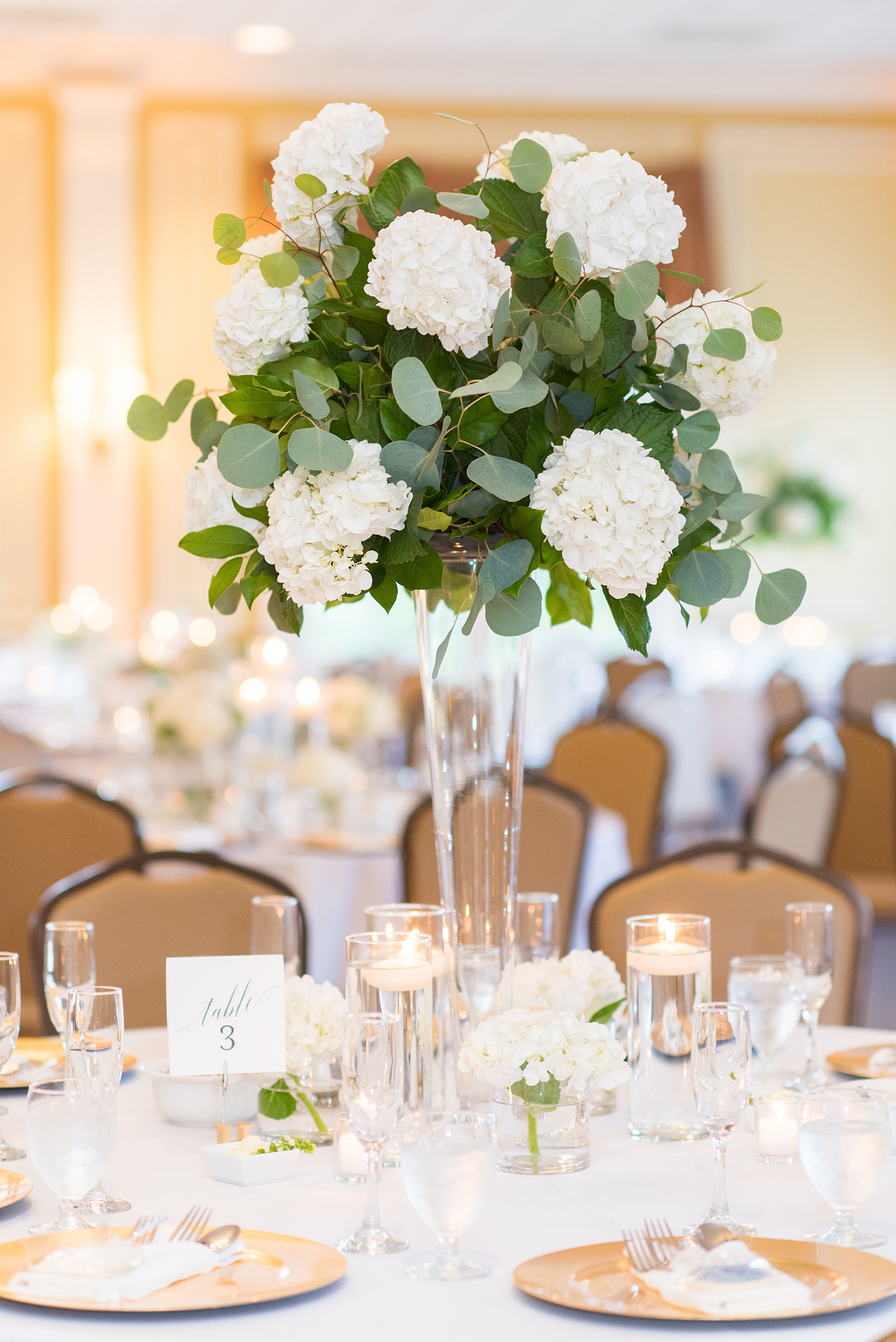 Pictures by Mikkel Paige Photography of a wedding in Durham, North Carolina. The beautiful hydrangea flowers from the day’s events adorned the party room that overlooked a pretty garden-like golf course. Some reception tables had low floral arrangements while others had high ones. Each had a script table number and candles. Click through to our website for the complete post! #durhamNC #northcarolinawedding #golfcoursewedding #CountryClub #DurhamWedding #summerwedding