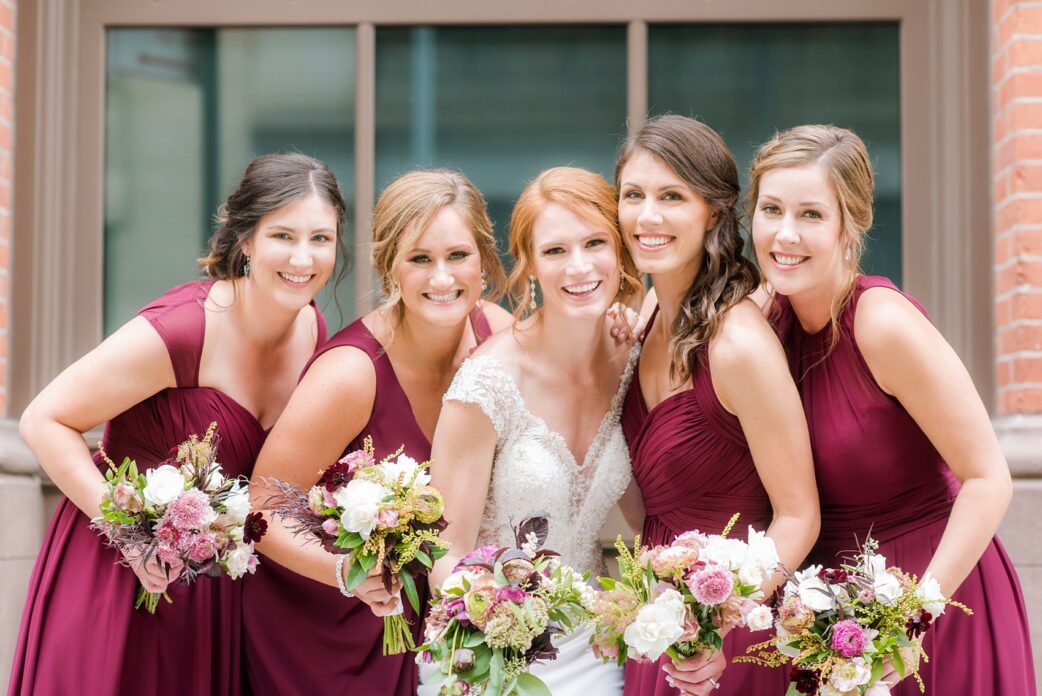 Wedding photos at Tribeca Rooftop by Mikkel Paige Photography, in NYC. This Manhattan venue has the perfect view of the New York City skyline including Freedom Tower. The bridal party wore mismatched cranberry dresses and held colorful fall flowers with dahlias and ranunculus. #ManhattanWedding #TribecaRooftop #TribecaRooftopWeddingPhotos #SeptemberWedding #BridalPhotos #BridePhotos #redheadbride #MikkelPaige #WeddingPhotos #BridalParty #RedBridesmaids #CranberryBridesmaids #RedWeddingInspiration #BerryWeddingInspiration