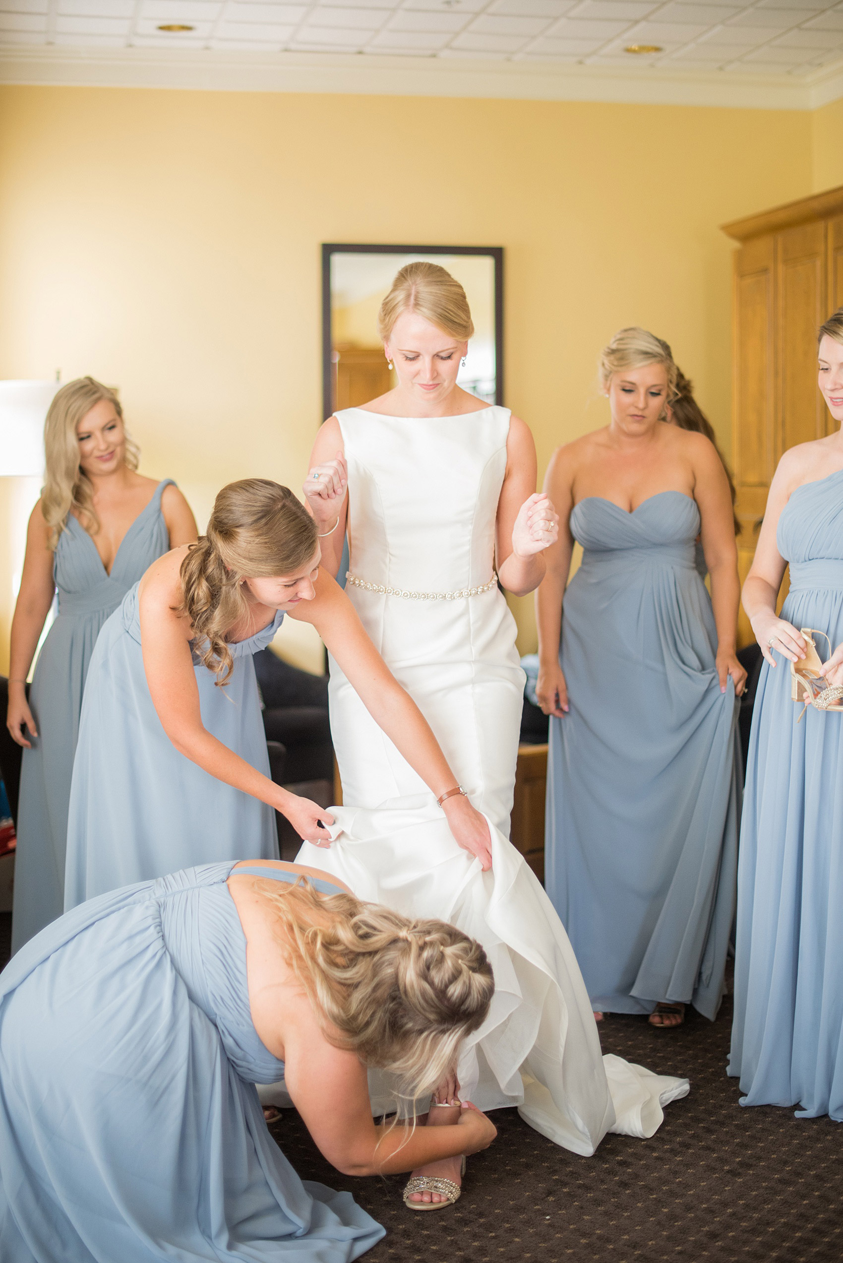 Pictures by Mikkel Paige Photography of a wedding in Durham, North Carolina. The bride carried hydrangea flowers for the garden-like golf course photos with her groom, and had a tulle overlay for the ceremony. She got into her low-back gown with the help of her bridesmaids, who were dressed in baby blue! Click through to the website post for complete details and more inspiration! #durhamNC #northcarolinawedding #DurhamWedding #summerwedding #weddinggown #lowbackweddinggown #gettingready #bride