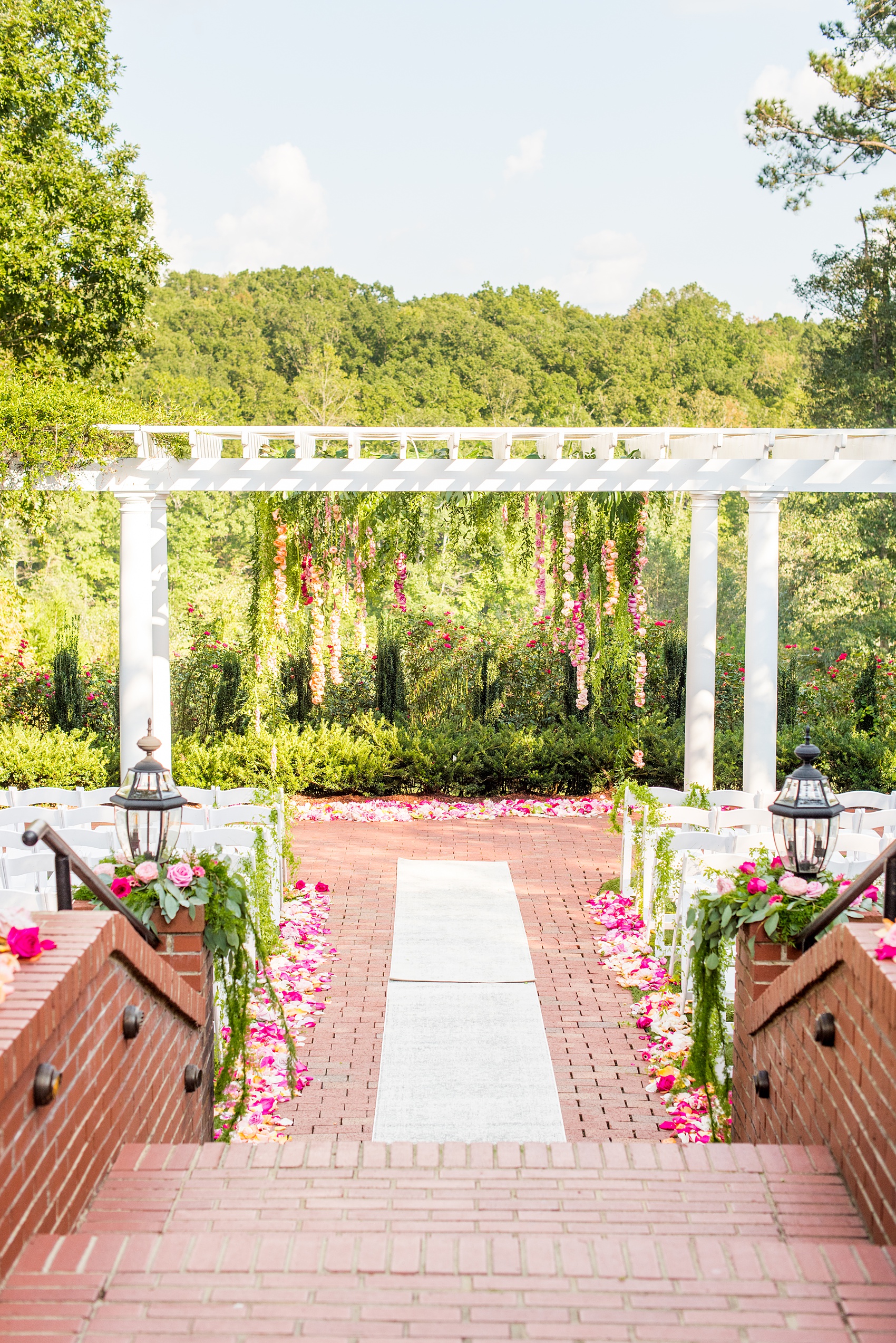 Highgrove Estate wedding photos by Mikkel Paige Photography. It’s a beautiful venue for a wedding large or small, near Raleigh, North Carolina. This wedding had fun signs, custom stationery and table numbers that said places the bride & groom travel to, and romantic candlelight planned by @asouthernsoiree. Click through to see the tropical green leaves, pink and orange flowers dripping from their outdoor ceremony space! #NorthCarolinaVenues #MikkelPaige #ASouthernSoiree #OutdoorCeremony