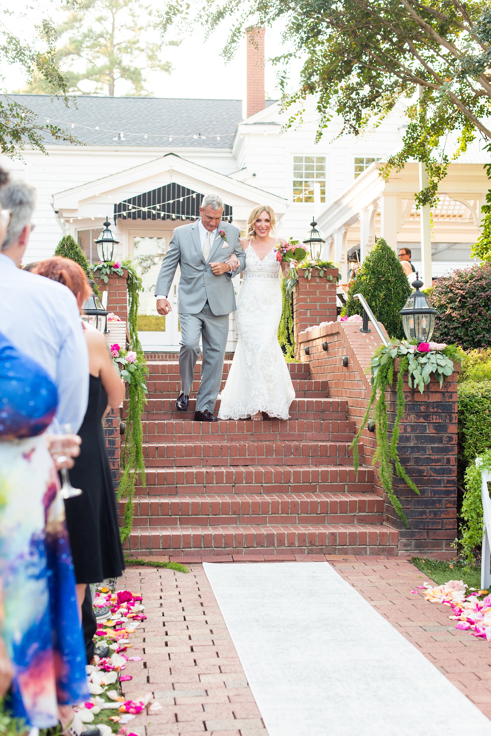 Highgrove Estate wedding photos by Mikkel Paige Photography. It’s a beautiful venue for a wedding large or small, near Raleigh, North Carolina. This wedding had fun signs, custom stationery and table numbers that said places the bride & groom travel to, and romantic candlelight planned by @asouthernsoiree. Click through to see the tropical green leaves, pink and orange flowers dripping from their outdoor ceremony space! #NorthCarolinaVenues #MikkelPaige #ASouthernSoiree #OutdoorCeremony