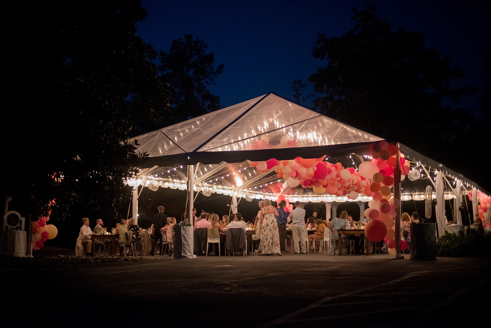 Highgrove Estate wedding photos by Mikkel Paige Photography. This beautiful venue works for a wedding large or small, near Raleigh, North Carolina. The couple had fun custom signs, stationery + table numbers that said places the couple travel to by @oneandonlypaper, + romantic candlelight in a lounge space planned by @asouthernsoiree. Click through to see the pink and green tropical flowers dripping from their tented reception space, also filled with balloons! #MikkelPaige #ASouthernSoiree