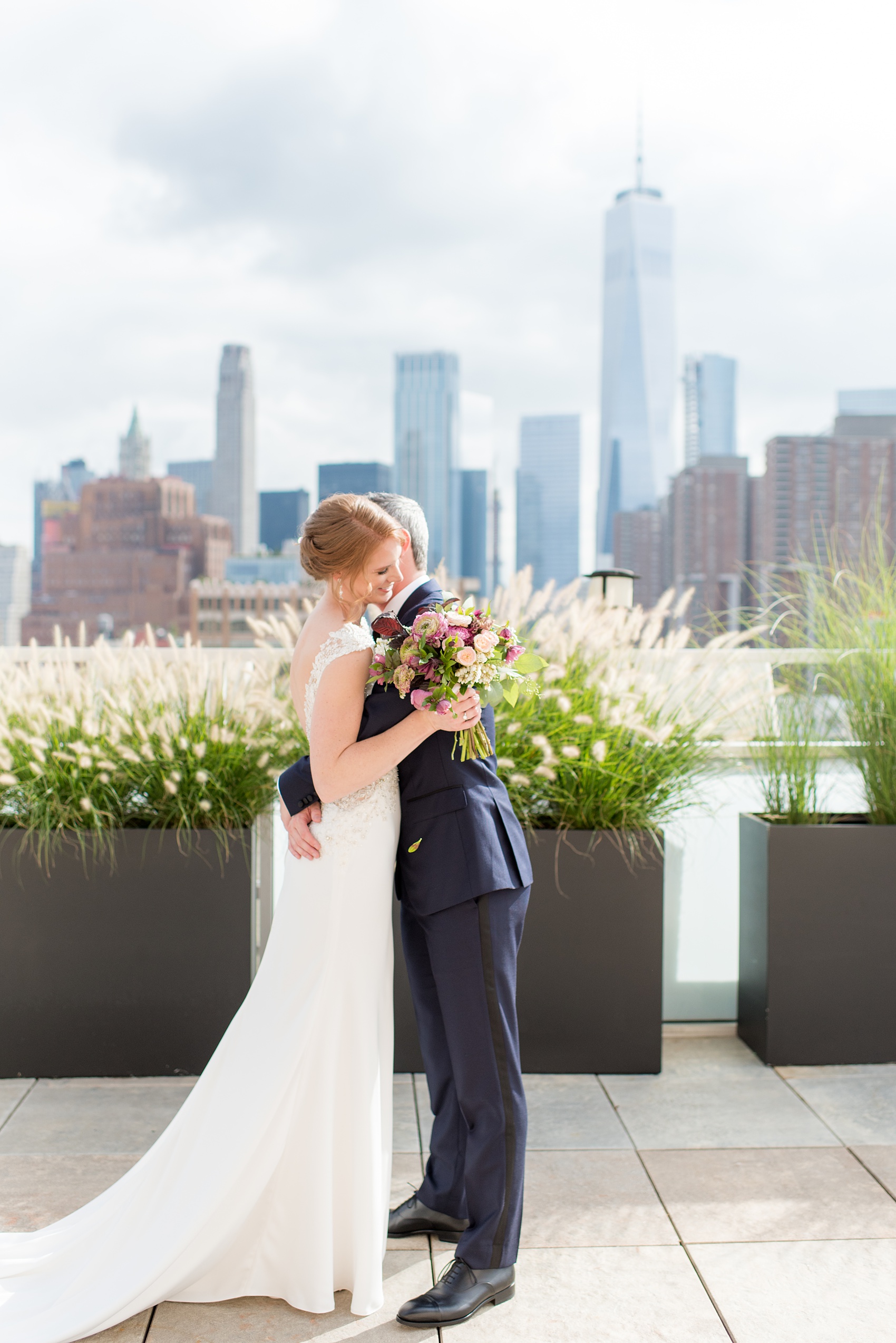 Photos of a NYC wedding venue, Tribeca Rooftop, by Mikkel Paige Photography. This ceremony and reception location has an outdoor space overlooking the Manhattan skyline. These pictures of the bride and groom will provide inspiration in New York! She wore a lace illusion gown with beading, her hair up, and carried a bouquet of fall flowers and he was in a navy suit. Click through for more details from this celebration! #TribecaRooftop #MikkelPaige #NYCwedding #NYCWeddingVenues #BrideandGroom 