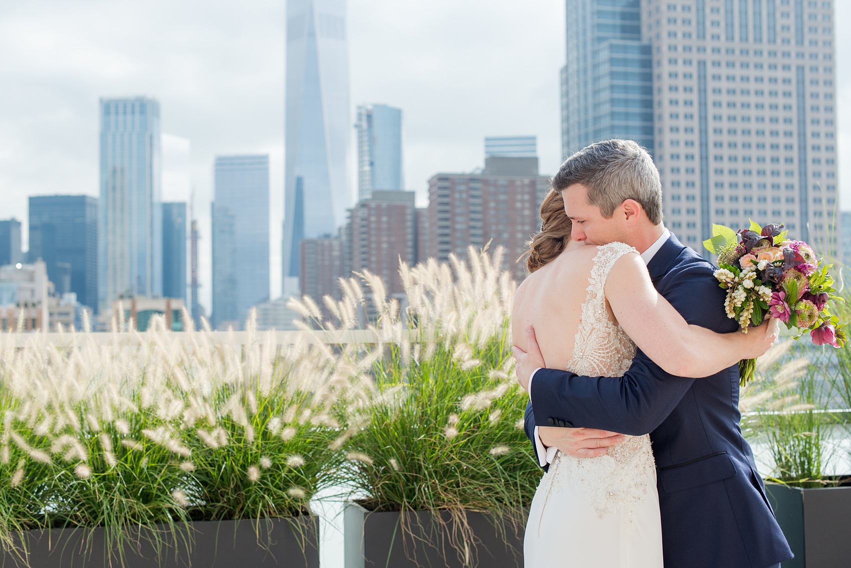 Photos of a NYC wedding venue, Tribeca Rooftop, by Mikkel Paige Photography. This ceremony and reception location has an outdoor space overlooking the Manhattan skyline. These pictures of the bride and groom will provide inspiration in New York! She wore a lace illusion gown with beading, her hair up, and carried a bouquet of fall flowers and he was in a navy suit. Click through for more details from this celebration! #TribecaRooftop #MikkelPaige #NYCwedding #NYCWeddingVenues #BrideandGroom 