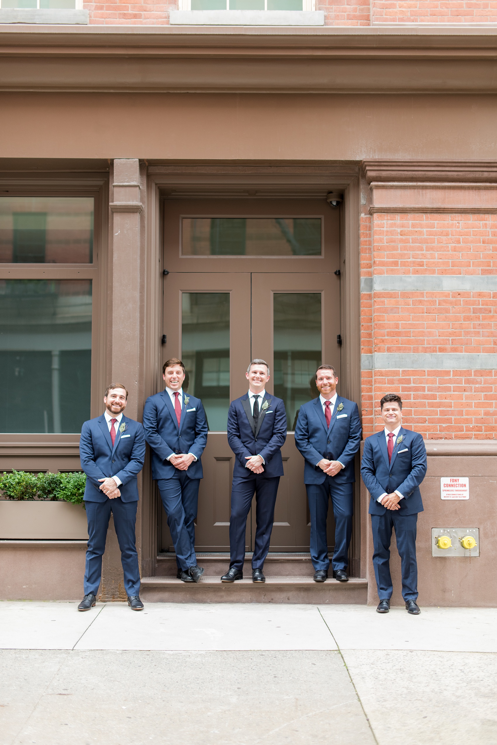 Photos of a NYC wedding venue, Tribeca Rooftop, by Mikkel Paige Photography. This ceremony and reception location has an outdoor space overlooking the Manhattan skyline. These pictures will provide inspiration in New York! The groom had his groomsmen by his side with simple leaf boutonnieres and navy suits, with a cranberry red tie to match the bridesmaids. Click through for more details from this celebration! #TribecaRooftop #MikkelPaige #NYCwedding #NYCWeddingVenues #NYCWeddingPhotography