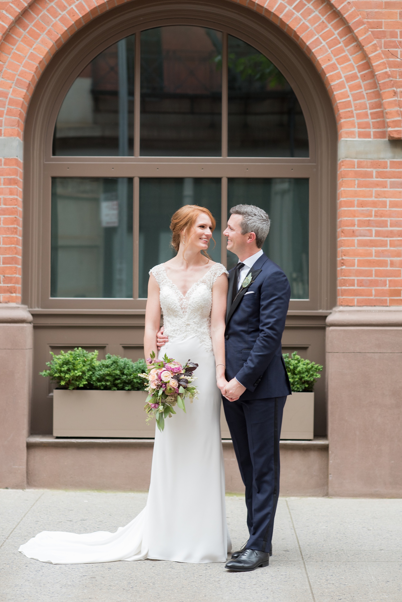 Photos of a NYC wedding venue, Tribeca Rooftop, by Mikkel Paige Photography. This ceremony and reception location has an outdoor space overlooking the Manhattan skyline. These pictures of the bride and groom will provide inspiration in New York! She wore a lace illusion gown with beading, her hair up, and carried a bouquet of fall flowers and he was in a navy suit. Click through for more details from this celebration! #TribecaRooftop #MikkelPaige #NYCwedding #NYCWeddingVenues #BrideandGroom 