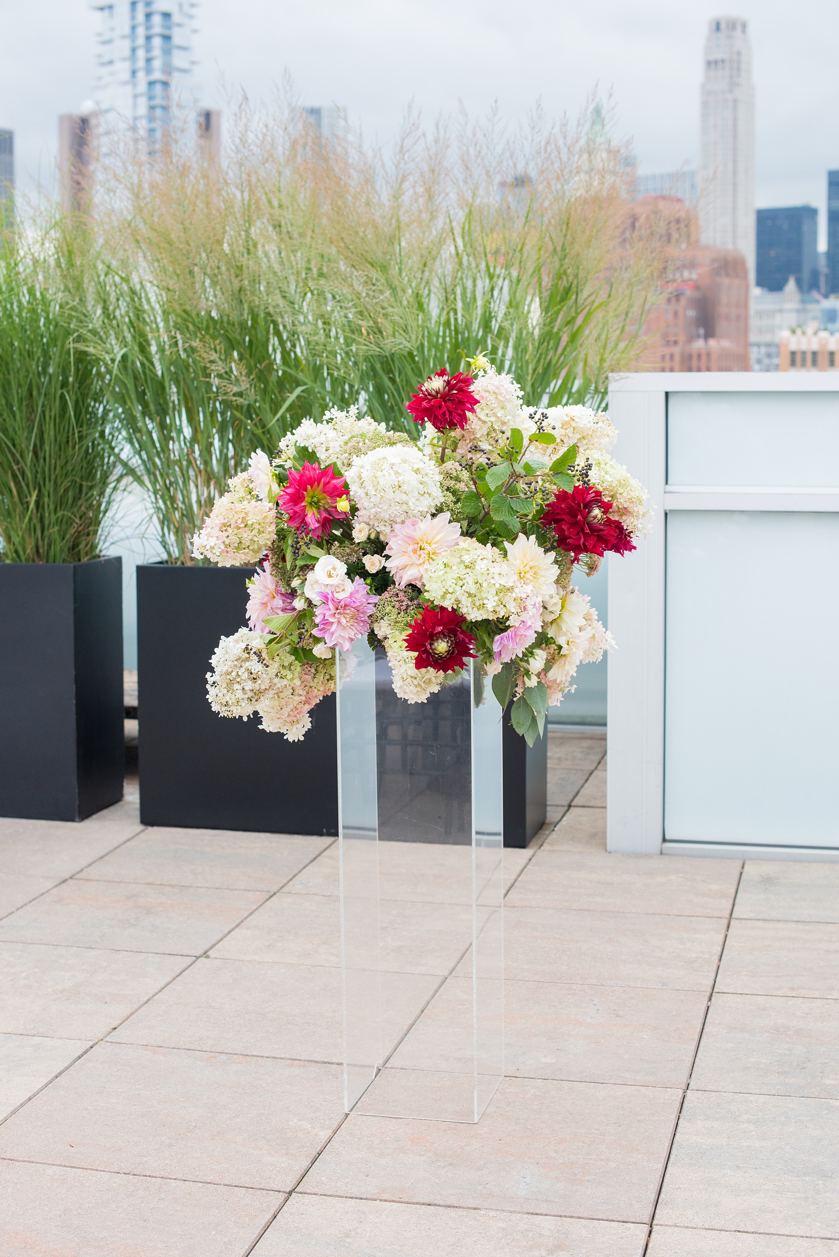 Photos of a NYC wedding venue, Tribeca Rooftop, by Mikkel Paige Photography. This ceremony and reception location has an outdoor space overlooking the Manhattan skyline. These pictures will provide inspiration in New York! Fall flowers were plentiful in bouquets and centerpieces, including red, purples, whites and pinks. Click through for more details from this celebration! #TribecaRooftop #MikkelPaige #NYCwedding #NYCWeddingVenues #NYCWeddingPhotography #FallFlowers #Ranunculus #Dahlias