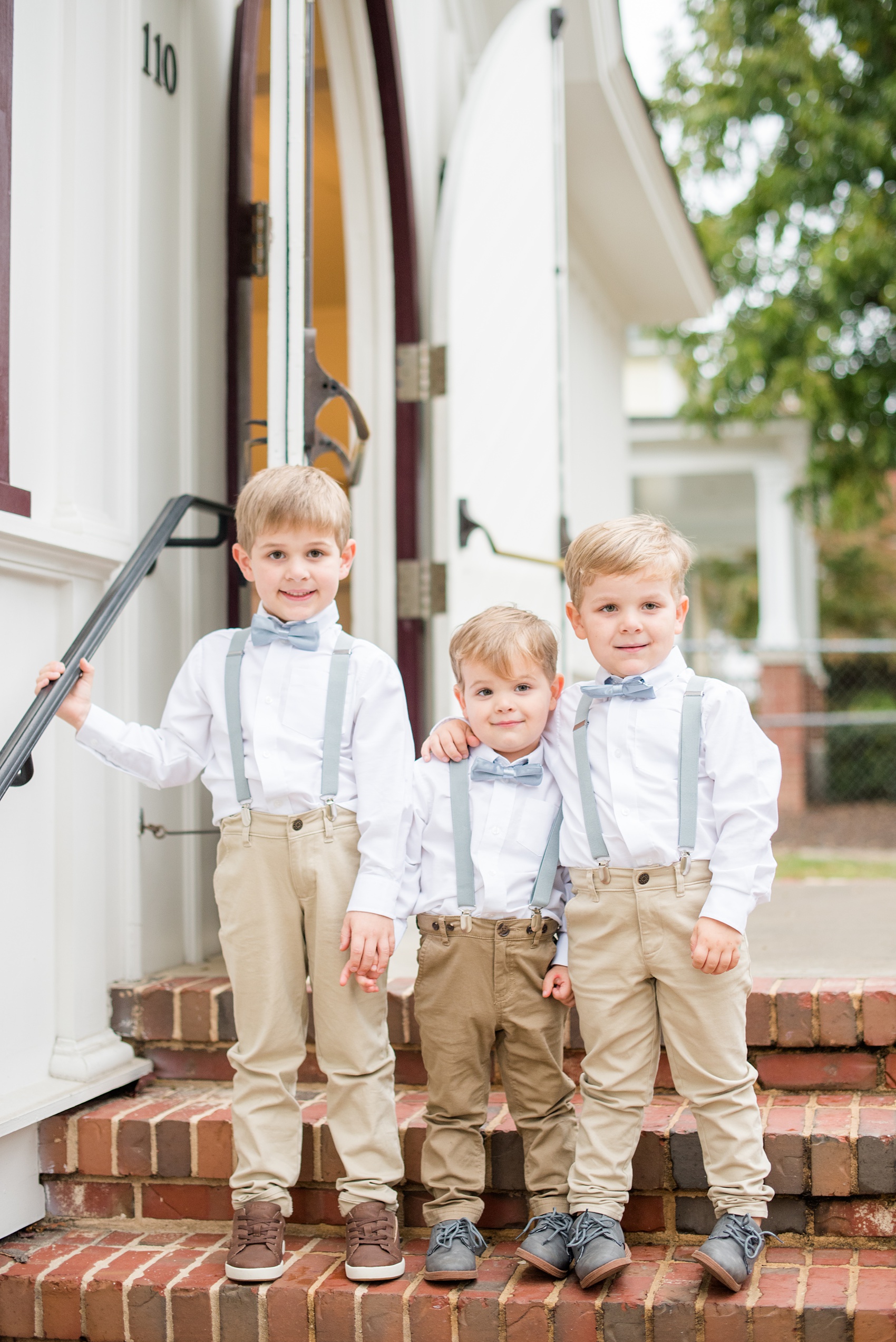 Mikkel Paige Photography captures a beautiful bride + groom during their fall wedding in Downtown Raleigh, North Carolina. All Saints Chapel was their ceremony + reception venue, which they decorated with gold + silver decor and autumn centerpieces. The ring bearers were captured in this picture with blue bow ties and suspenders for their dapper style. Click through for candid moments from this celebration! #MikkelPaige #RaleighWeddingPhotographer #RaleighWeddingVenue #DowntownRaleighWedding