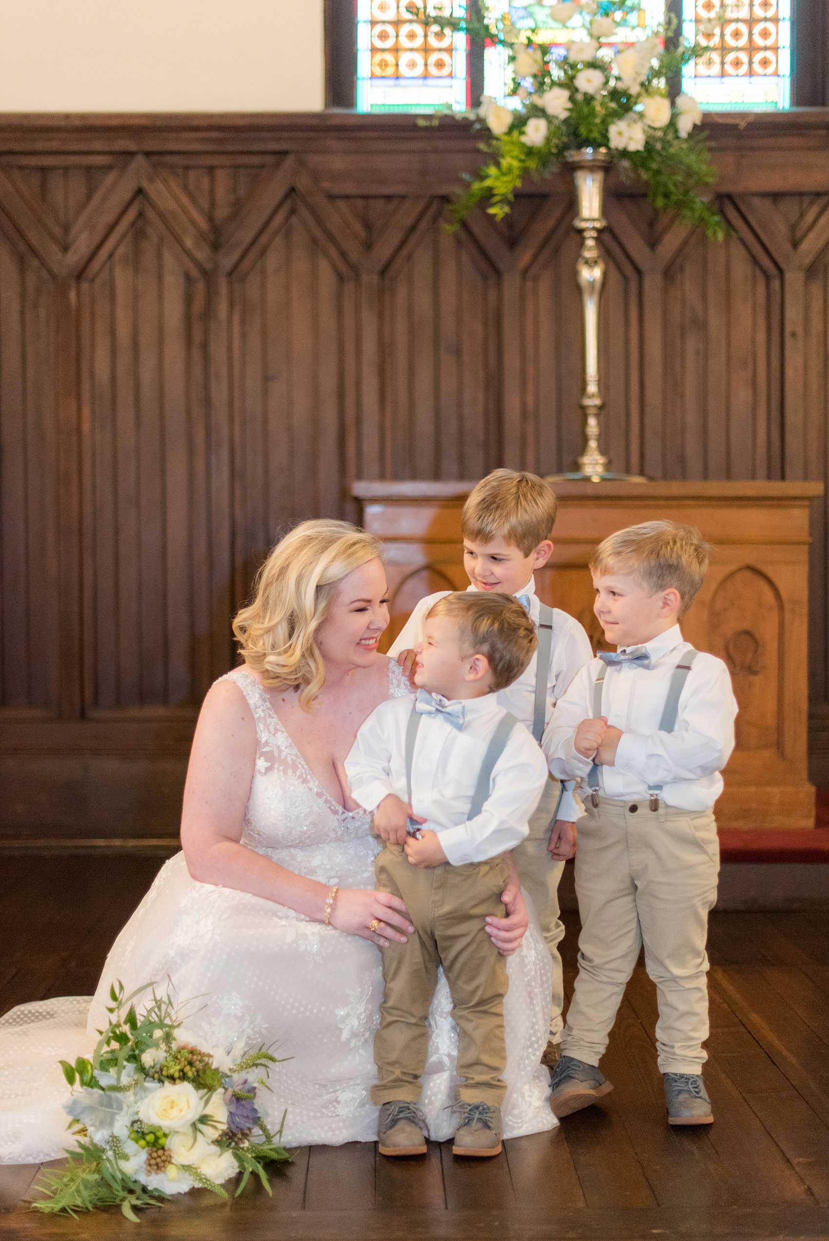 Mikkel Paige Photography captures a beautiful bride + groom during their fall wedding in Downtown Raleigh, North Carolina. All Saints Chapel was their ceremony + reception venue, which they decorated with gold + silver decor and autumn centerpieces. The bride was captured in a happy candid moment in this picture with her three ring bearers. Click through for all the details from this amazing celebration! #MikkelPaige #RaleighWeddingPhotographer #RaleighWeddingVenue #DowntownRaleighWedding