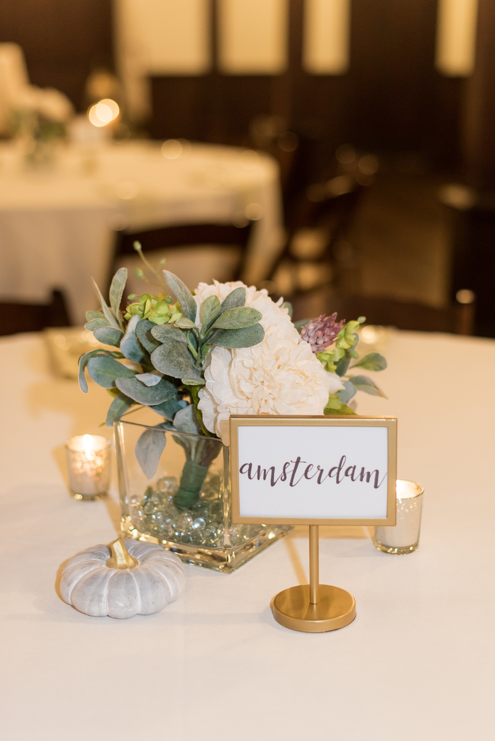 Mikkel Paige Photography captures beautiful details and fall styles during a wedding in Downtown Raleigh, North Carolina. All Saints Chapel venue was decorated with gold + silver decor and autumn accents. Custom signage was on tables at the reception with names of places the bride and groom traveled. Click through for all the event details from this celebration! #MikkelPaige #RaleighWeddingPhotographer #RaleighWedding #DowntownRaleighWedding #travelwedding #brideandgroom