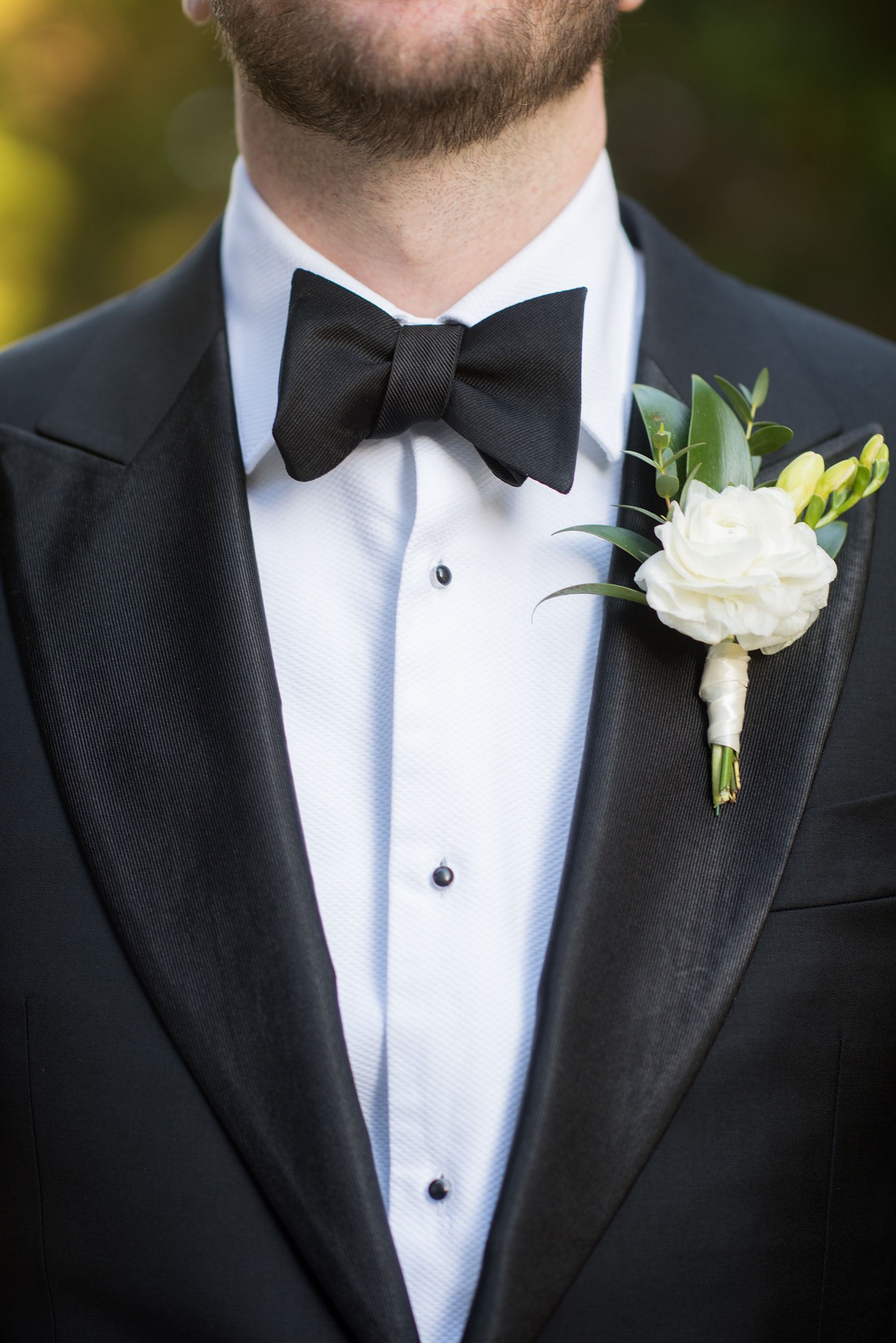 A fall wedding with burgundy, dusty rose and grey details. The groom wore a white ranunculus boutonniere and timeless black tuxedo and bow tie. Mikkel Paige Photography, photographer in Greenville NC and Raleigh captured this wedding at Rock Springs Center, planned by @vivalevent. Click through for more details and pictures from this autumn day! #mikkelpaige #northcarolinawedding #southernwedding #burgundywedding #fallbouquet #groomstyle #tuxedo #ranunculus #boutonniere