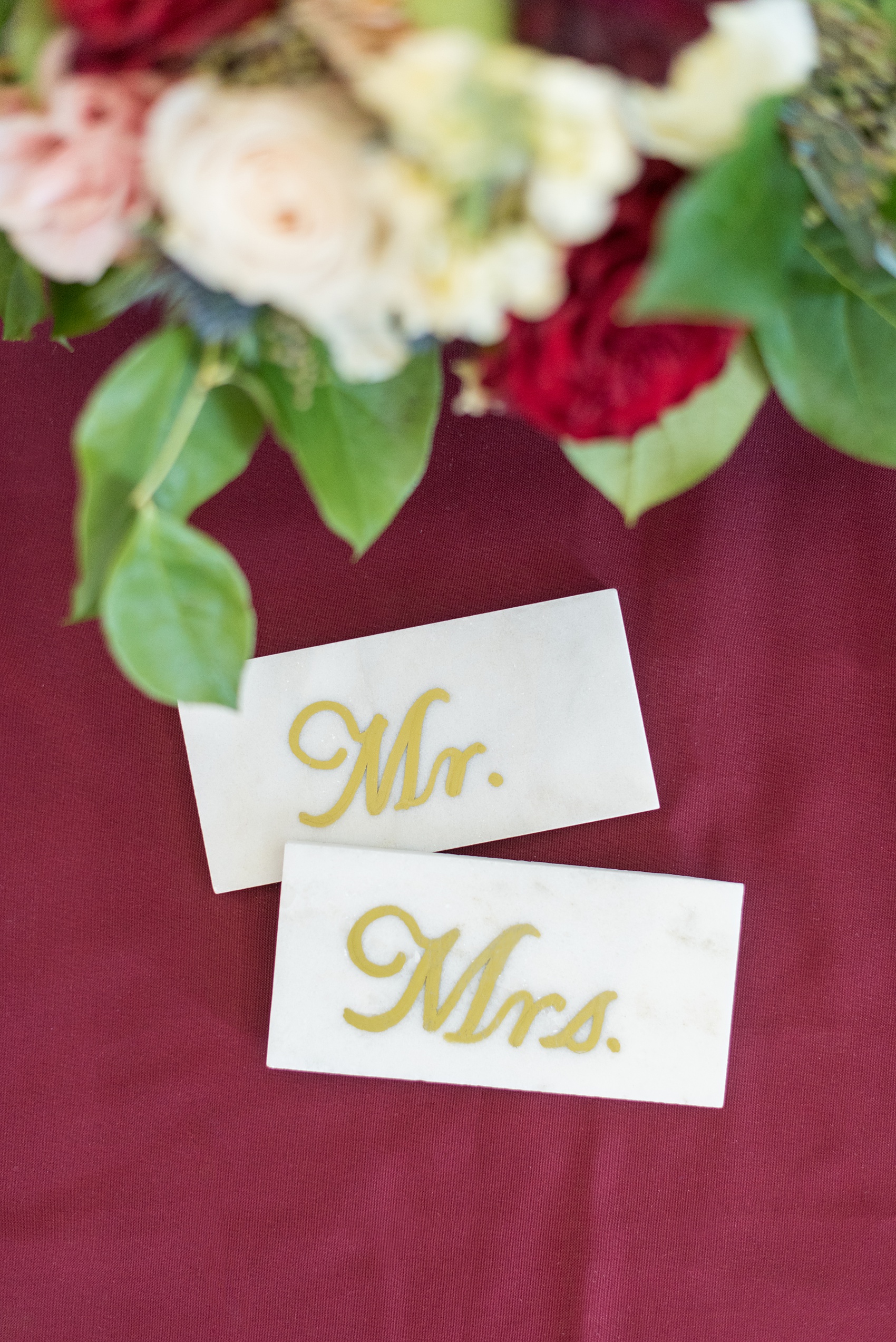 A fall wedding with burgundy, dusty rose and grey details. The bride and groom had special sweetheart table tiles for "Mr. and Mrs." seats at the front of the venue with gold script writing. Mikkel Paige Photography, photographer in Greenville NC and Raleigh captured this wedding at Rock Springs Center, planned by @vivalevent. Click through for more details and pictures from their day! #mikkelpaige #northcarolinawedding #southernwedding #weddingreception #burgundywedding #escortcards #MrandMrs