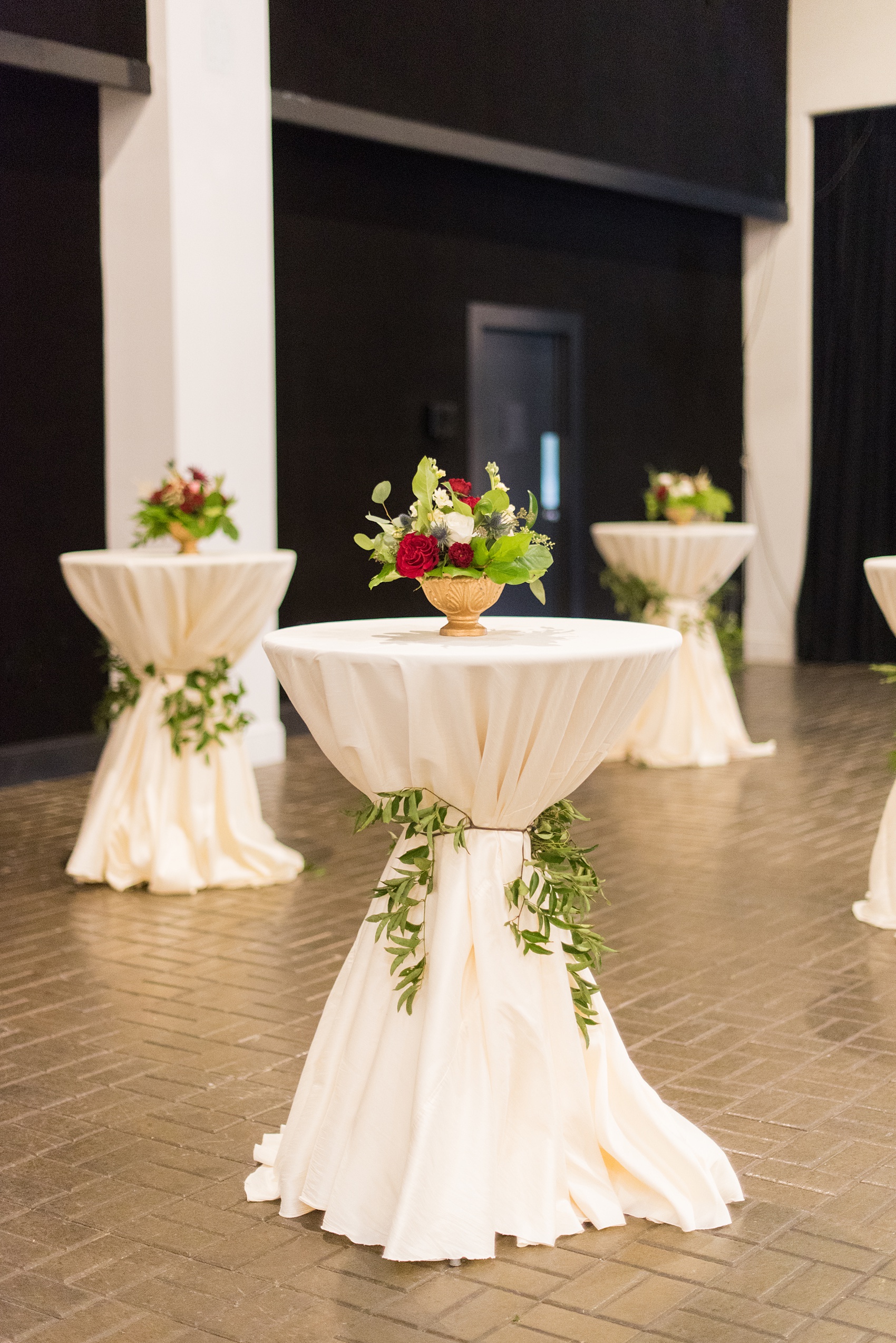 A fall wedding with burgundy, dusty rose and grey details. The reception room was filled with high + low floral centerpieces, with red and pink details, + lots of candlelight. Marble tiles served as table numbers. Mikkel Paige Photography, photographer in Greenville NC and Raleigh, captured this wedding at Rock Springs Center, planned by @vivalevent. Click through for more details and pictures from their day! #mikkelpaige #northcarolinawedding #southernwedding #weddingreception #burgundywedding