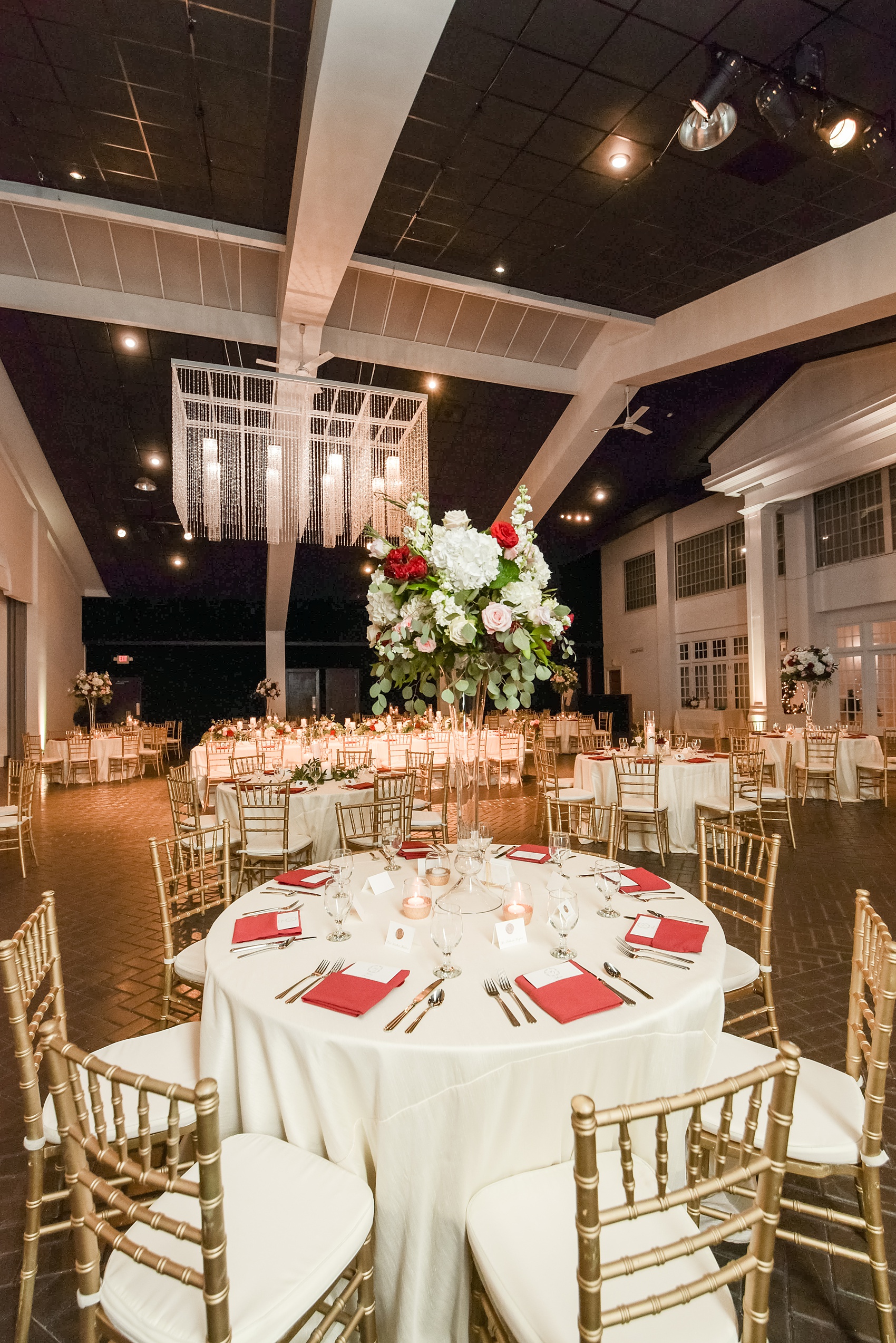 A fall wedding with burgundy, dusty rose and grey details. The reception room was filled with high + low floral centerpieces, with red and pink details, + lots of candlelight. Marble tiles served as table numbers. Mikkel Paige Photography, photographer in Greenville NC and Raleigh, captured this wedding at Rock Springs Center, planned by @vivalevent. Click through for more details and pictures from their day! #mikkelpaige #northcarolinawedding #southernwedding #weddingreception #burgundywedding