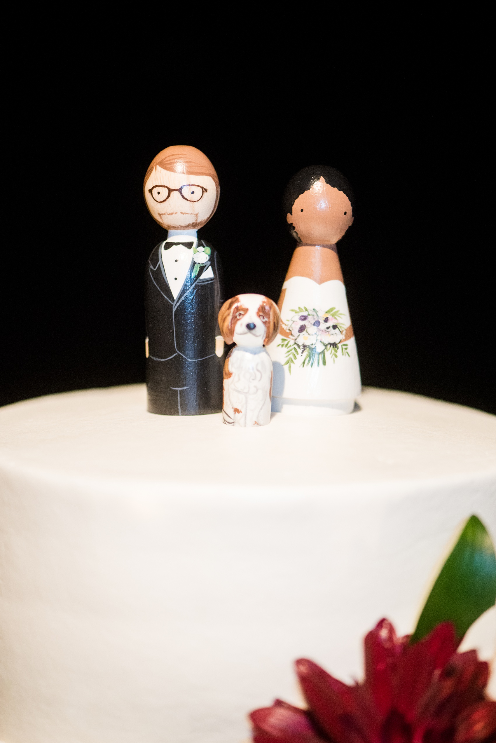 A fall wedding with burgundy, dusty rose and grey details. The couple cut their three tiered, white fondant cake with a peg figure cake topper with the bride, groom, and their dog. Mikkel Paige Photography, photographer in Greenville NC and Raleigh, captured this wedding at Rock Springs Center, planned by @vivalevent. Click through for more details and pictures from their day! #mikkelpaige NCwedding #northcarolinawedding #southernwedding #caketopper #dahlias #burgundywedding