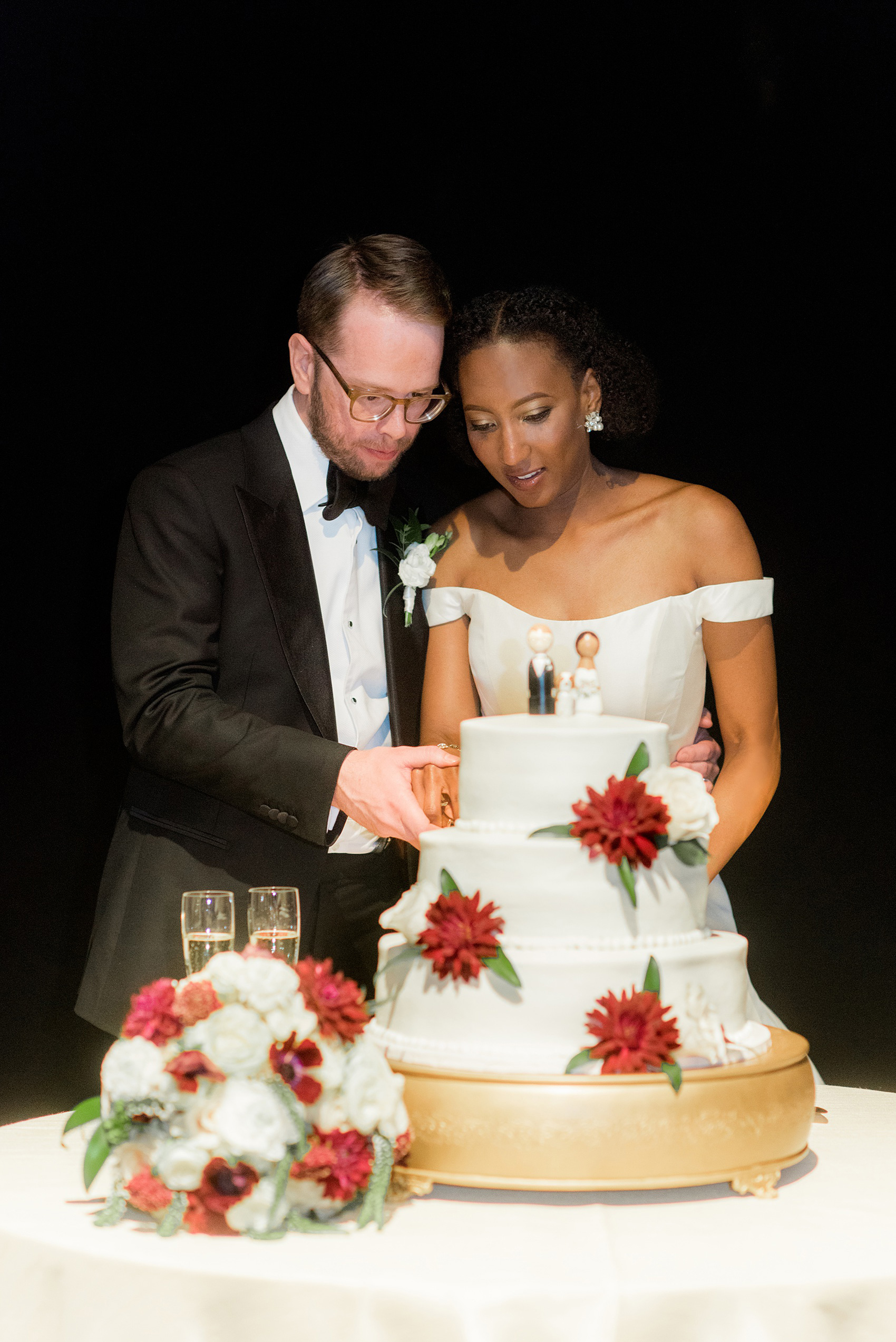 A fall wedding with burgundy, dusty rose and grey details. The couple cut their three tiered, white fondant cake with a peg figure cake topper with the bride, groom, and their dog. Mikkel Paige Photography, photographer in Greenville NC and Raleigh, captured this wedding at Rock Springs Center, planned by @vivalevent. Click through for more details and pictures from their day! #mikkelpaige NCwedding #northcarolinawedding #southernwedding #caketopper #dahlias #burgundywedding