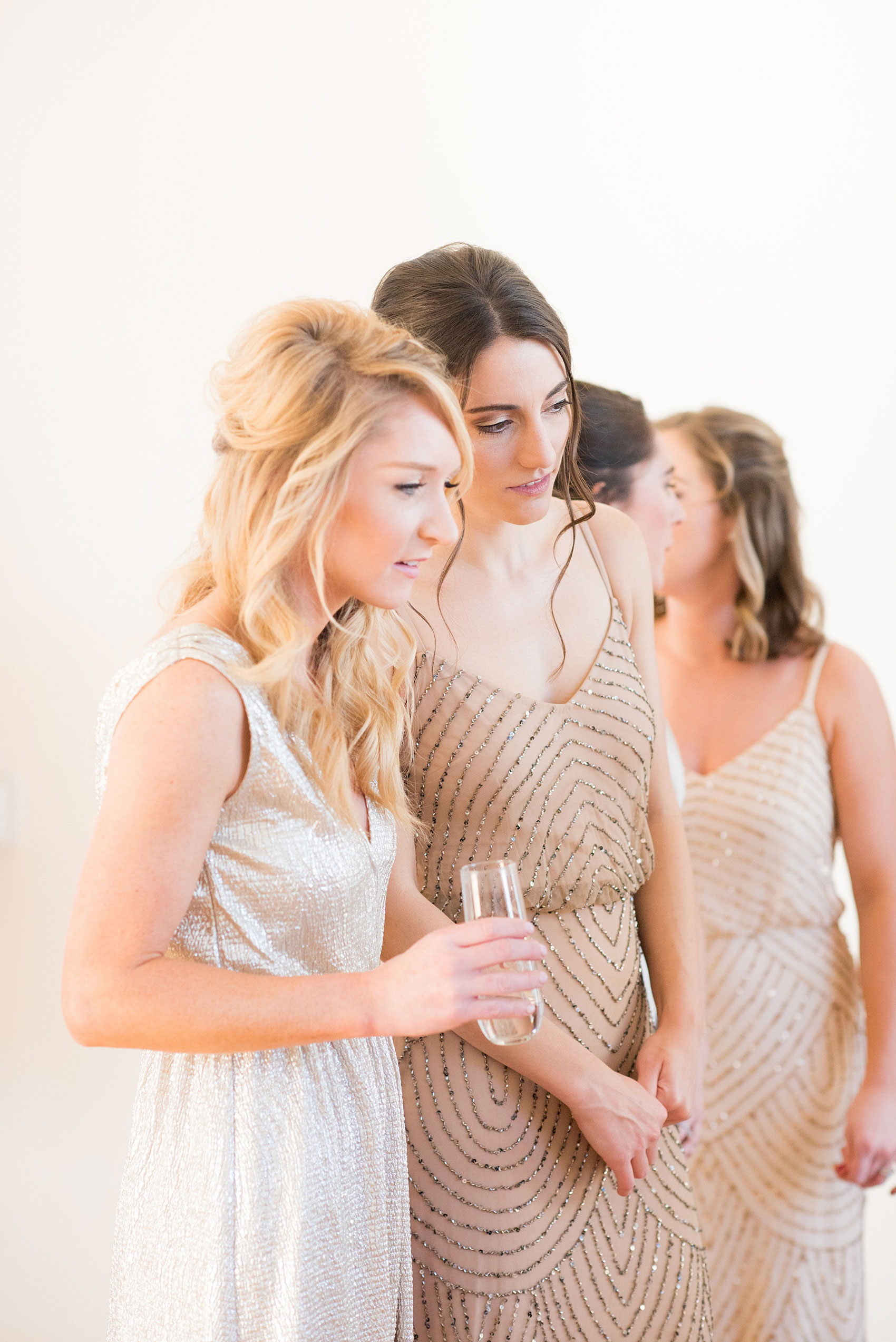 Pictures from a Christmas inspired wedding in downtown Raleigh, North Carolina by Mikkel Paige Photography. The bride and bridesmaids got ready for the church ceremony and reception at The Stockroom at 230, at The Glass Box in mismatched pink dresses. Click through for more ideas from a beautiful celebration, including decor photos in a green and gold decor palette. #mikkelpaige #raleighweddingphotographer #downtownRaleigh #greenandgoldwedding #gettingready #christmaswedding #bridesmaids #bridal