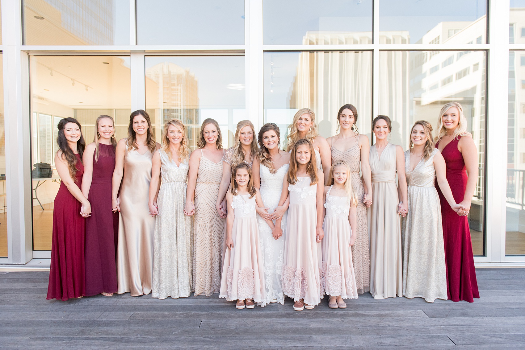 Pictures from a Christmas inspired wedding in downtown Raleigh, North Carolina by Mikkel Paige Photography. The bridesmaids got ready at The Glass Box and wore mismatched pink and burgundy gowns. Click through for more ideas from a beautiful celebration, including decor photos in a green and gold decor palette for their reception at The Stockroom at 230. #mikkelpaige #raleighweddingphotographer #downtownRaleigh #weddingparty #bridalparty #pinkbridesmaids #sequingowns