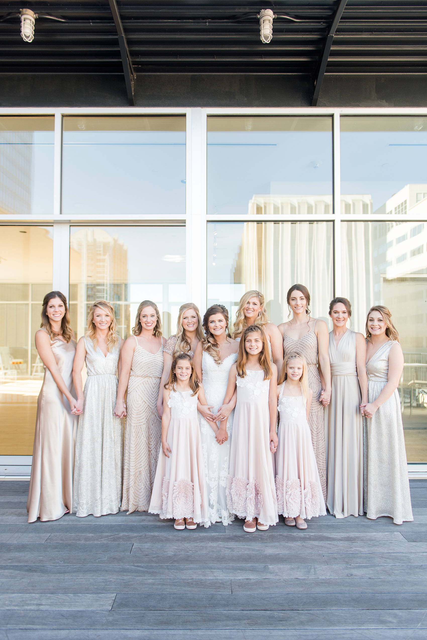 Pictures from a Christmas inspired wedding in downtown Raleigh, North Carolina by Mikkel Paige Photography. The bridesmaids got ready at The Glass Box and wore mismatched pink gowns. Click through for more ideas from a beautiful celebration, including decor photos in a green and gold decor palette for their reception at The Stockroom at 230. #mikkelpaige #raleighweddingphotographer #downtownRaleigh #weddingparty #bridalparty #pinkbridesmaids #sequingowns #winterwedding