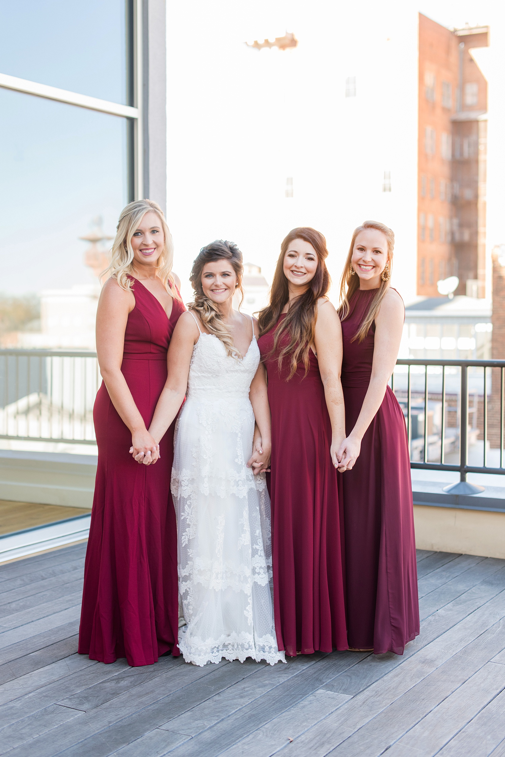 Pictures from a Christmas inspired wedding in downtown Raleigh, North Carolina by Mikkel Paige Photography. The bridesmaids got ready at The Glass Box and some wore burgundy gowns. Click through to see the entire style with others in pink mismatched gowns from a beautiful celebration, including decor photos in a green and gold decor palette for their reception at The Stockroom at 230. #mikkelpaige #raleighweddingphotographer #downtownRaleigh #bridalparty #burgundybridesmaids