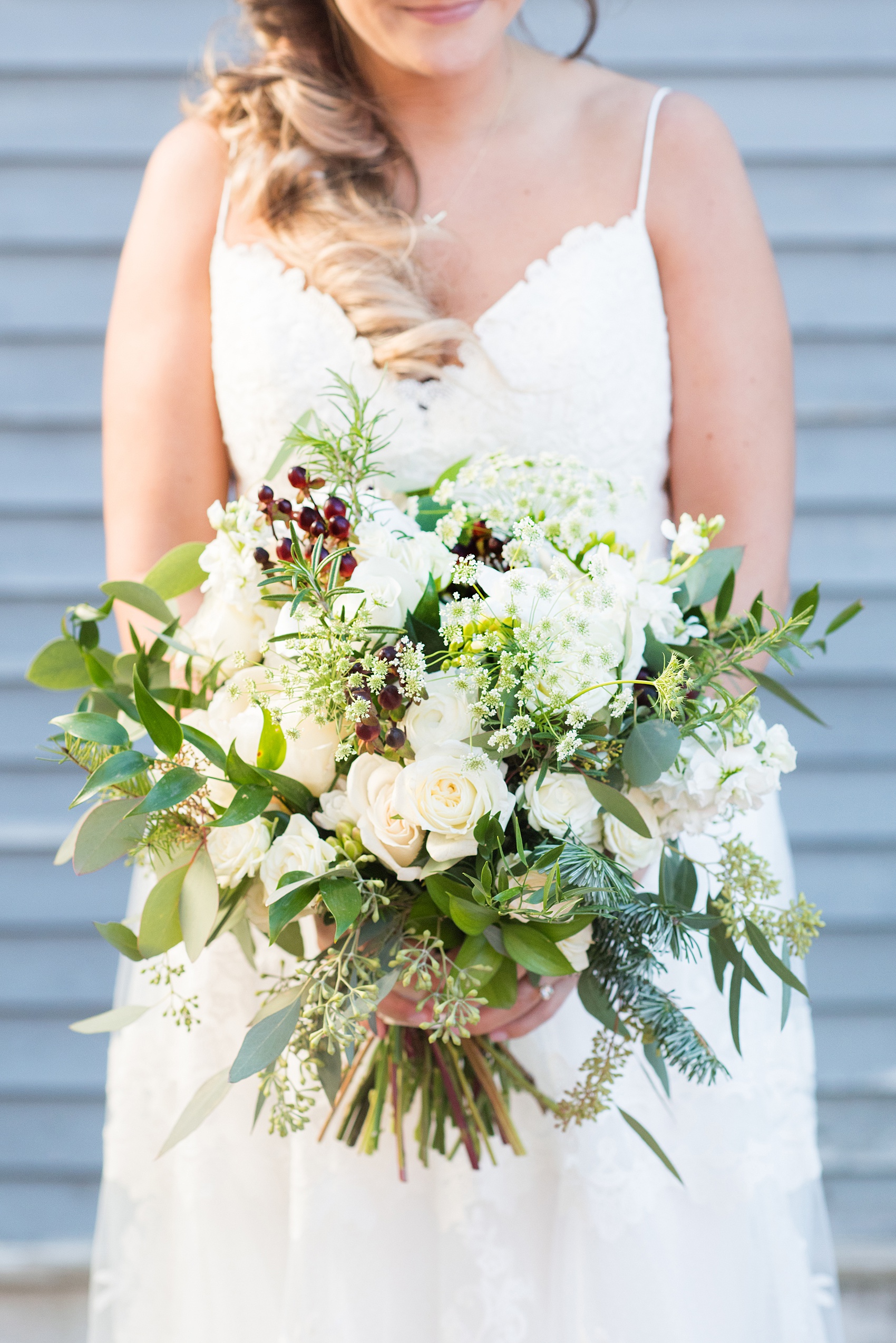 Pictures from a Christmas inspired wedding in downtown Raleigh, North Carolina by Mikkel Paige Photography. The bride carried a holiday bouquet for her church ceremony at The Stockroom at 230 with rosemary, ranunculus and berries. Click through for more ideas from their beautiful celebration, including decor photos in a green and gold decor palette for their reception. #mikkelpaige #raleighweddingphotographer #downtownRaleigh #greenandgoldwedding #gettingready #holidaybouquet #christmaswedding