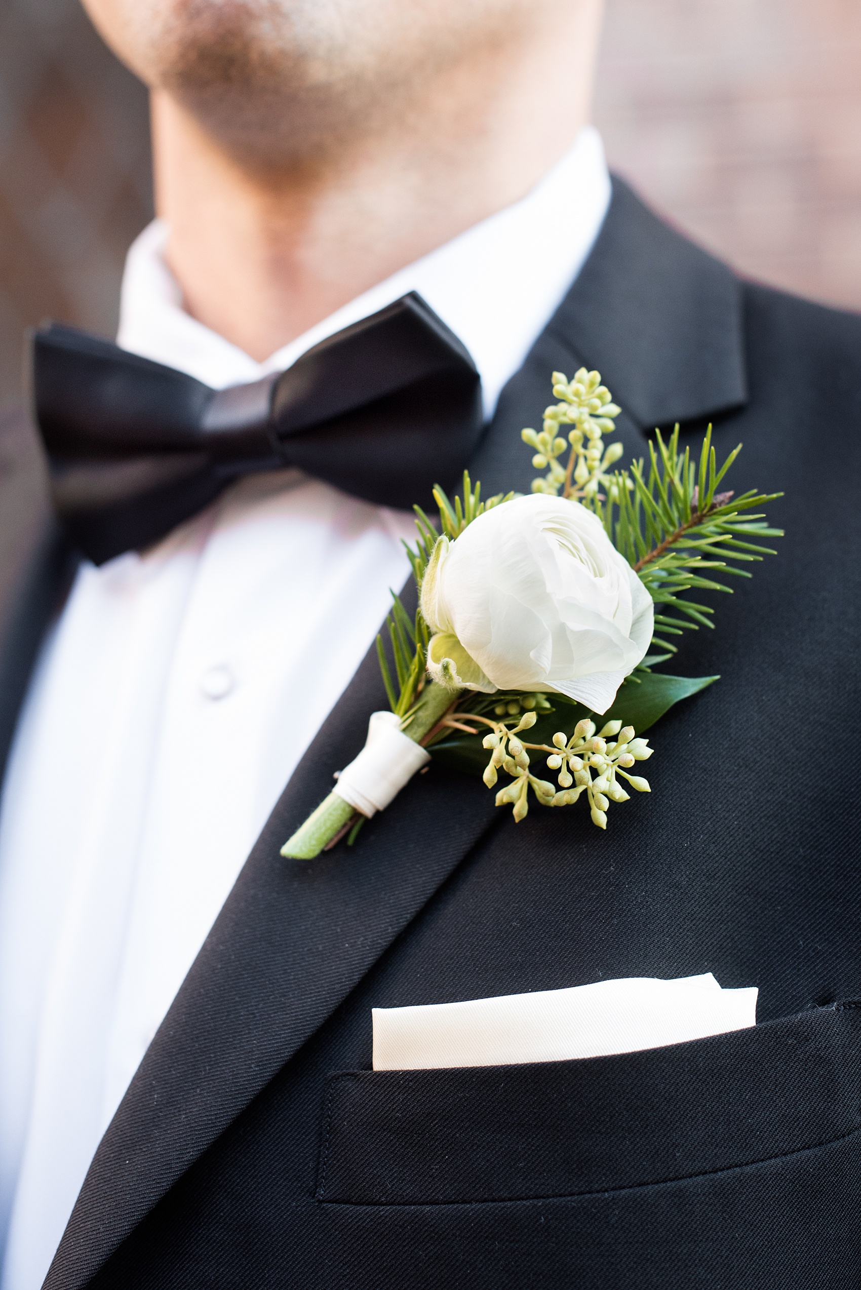 Pictures from a Christmas inspired wedding in downtown Raleigh, North Carolina by Mikkel Paige Photography. The groomsmen wore black tuxedos and wore holiday inspired boutonnieres. Click through for more outdoor and indoor ideas from this beautiful celebration, including decor photos in a green and gold decor palette for their reception at The Stockroom at 230. #mikkelpaige #raleighweddingphotographer #downtownRaleigh #weddingparty #holidaywedding #winterwedding #whiteboutonierre