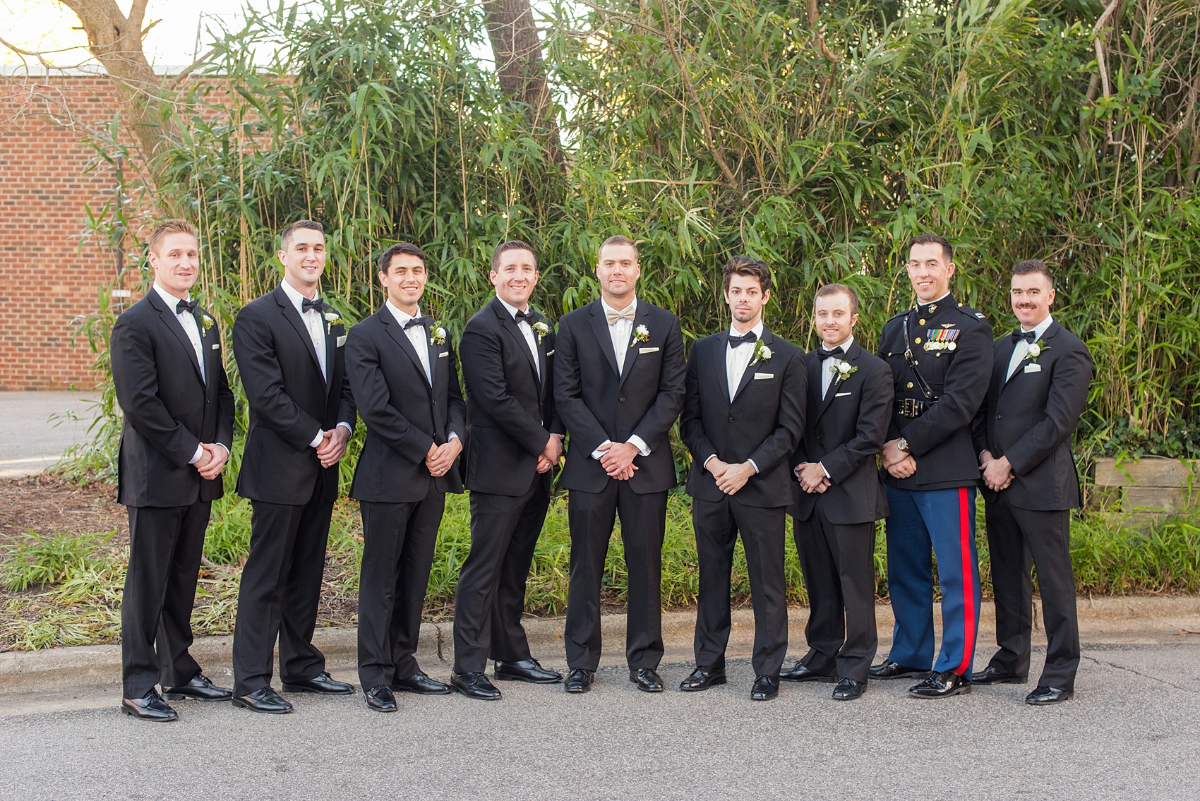 Pictures from a Christmas inspired wedding in downtown Raleigh, North Carolina by Mikkel Paige Photography. The groomsmen wore black tuxedos and wore holiday inspired boutonnieres. Click through for more outdoor and indoor ideas from this beautiful celebration, including decor photos in a green and gold decor palette for their reception at The Stockroom at 230. #mikkelpaige #raleighweddingphotographer #downtownRaleigh #weddingparty #holidaywedding #winterwedding #groomsmen