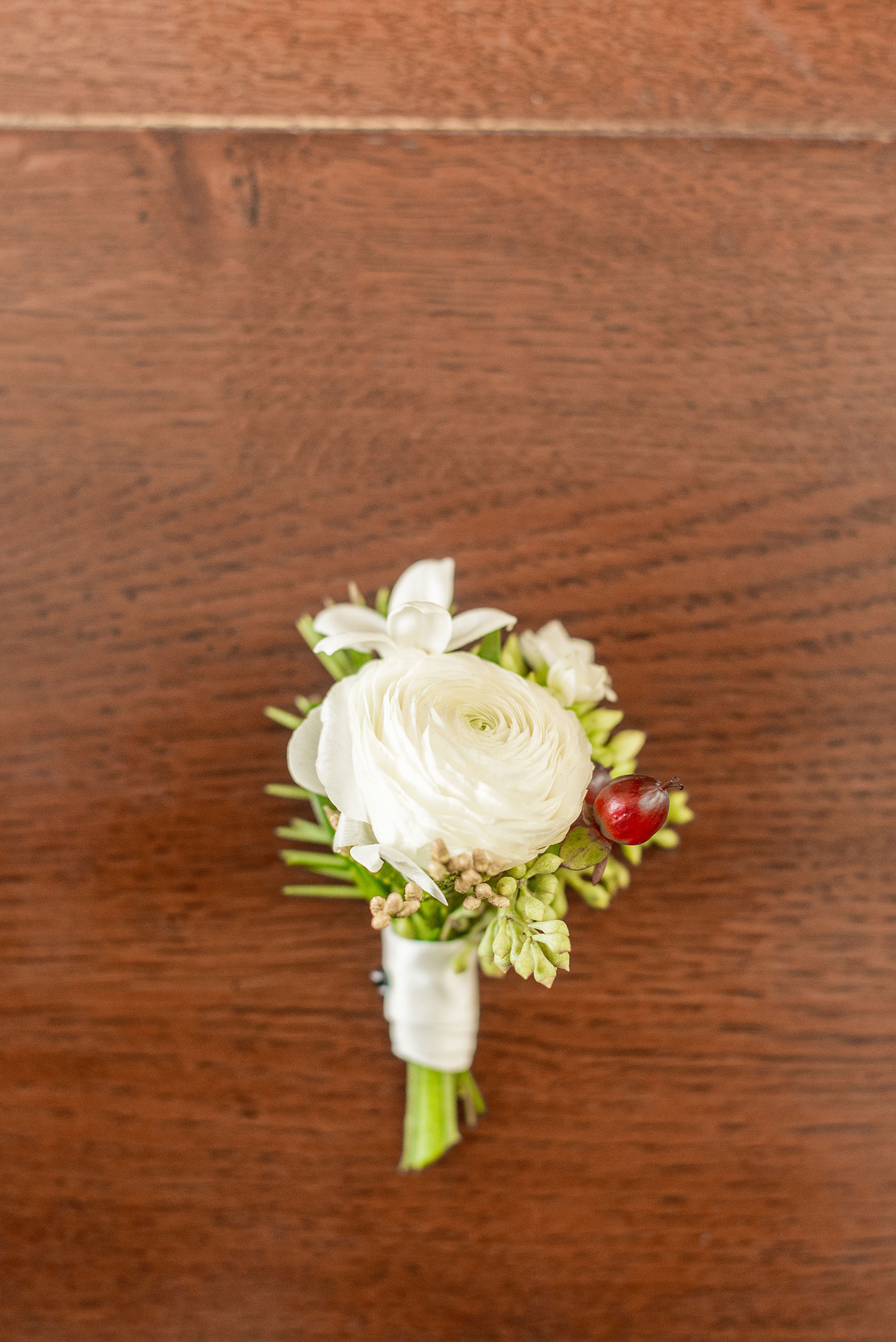 Pictures from a Christmas inspired wedding in downtown Raleigh, North Carolina by Mikkel Paige Photography. The groomsmen wore holiday inspired boutonnieres with white ranunculus and evergreen sprigs. Click through for more holiday wedding ideas from this beautiful celebration, including decor photos in a green and gold decor palette for their reception at The Stockroom at 230. #mikkelpaige #raleighweddingphotographer #downtownRaleigh #holidaywedding #winterwedding #whiteboutonierre