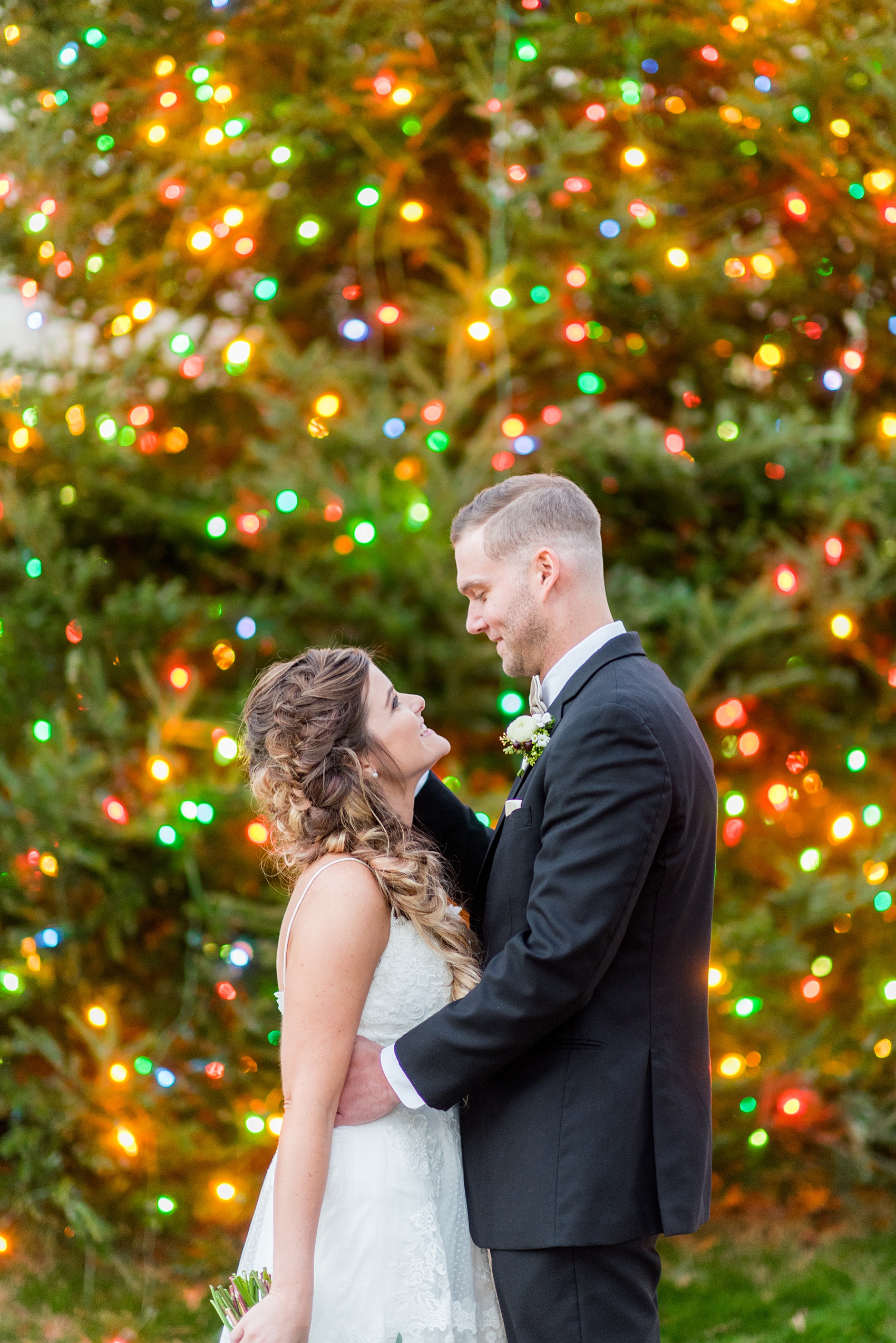 Pictures from a holiday inspired wedding in downtown Raleigh, North Carolina by Mikkel Paige Photography. The bride and groom took outdoor portraits by the capital with the Christmas lights twinkling behind them. She had a beautiful goddess fishtail braid hair style and lace gown. Click through for more ideas from a beautiful celebration, including details + decor photos in a green + gold decor palette for their reception. #mikkelpaige #raleighweddingphotographer #downtownRaleigh #brideandgroom 