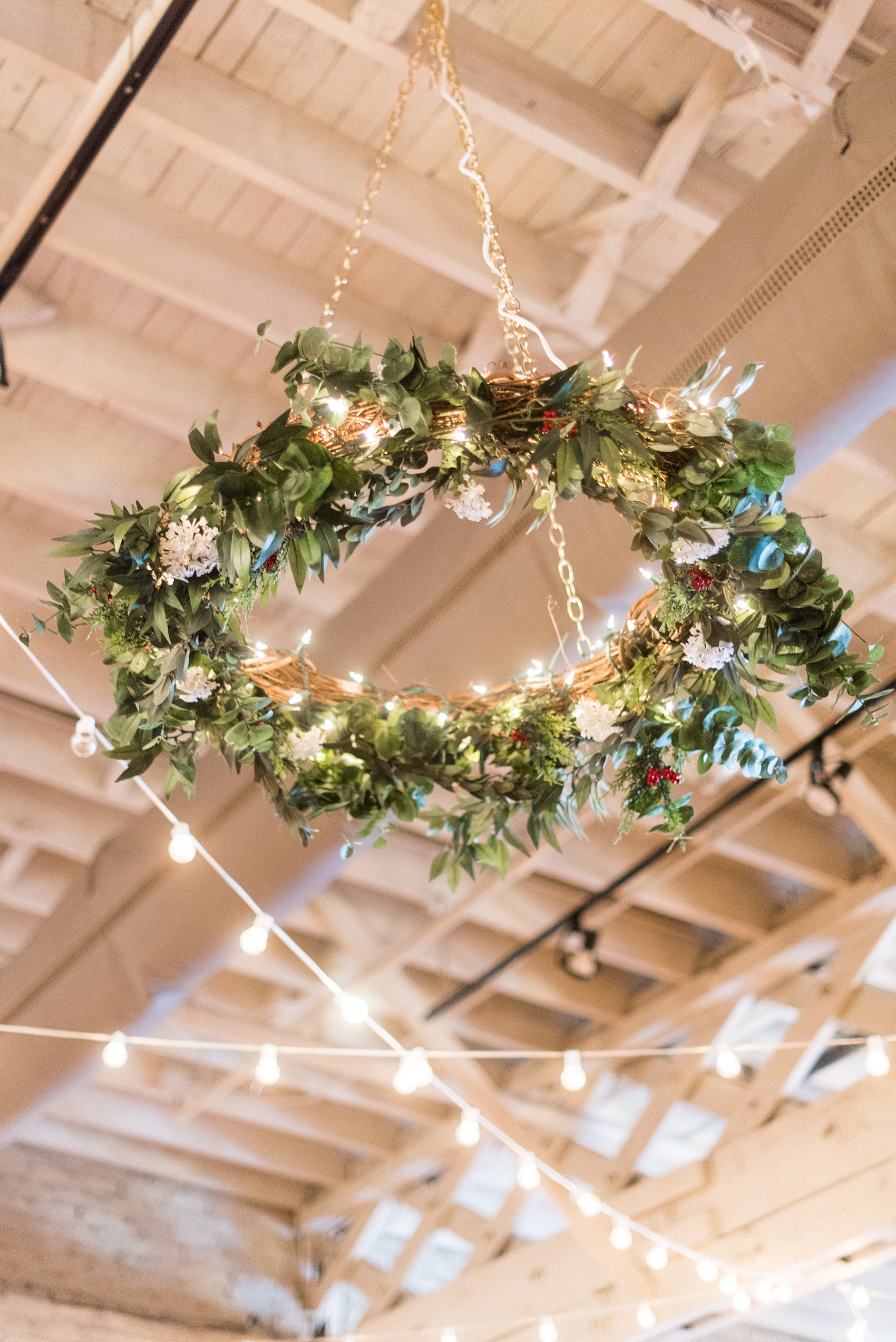 Pictures from a Christmas inspired wedding in downtown Raleigh, North Carolina by Mikkel Paige Photography. The bride and groom had a reception at The Stockroom at 230 with green and gold decor details, and a hanging evergreen flower installation. Mercury glass held warm candles. Click through for more ideas from their beautiful celebration! #mikkelpaige #raleighweddingphotographer #downtownRaleigh #greenandgoldwedding #holidaywedding #ChristmasWedding #hangingflowers #weddingwreath