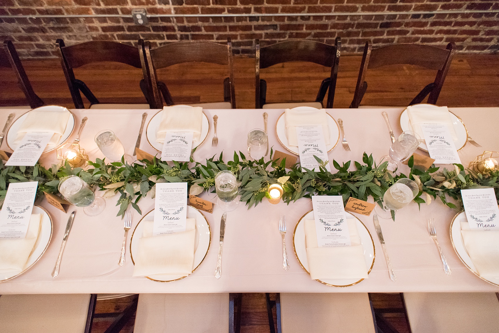 Pictures from a Christmas inspired wedding in downtown Raleigh, North Carolina by Mikkel Paige Photography. The bride and groom had a reception at the rustic venue, The Stockroom at 230, with pink linens, candlelight and greenery details. Click through for more ideas from their beautiful celebration with a pink and gold palette! #mikkelpaige #raleighweddingphotographer #downtownRaleigh #holidaywedding #ChristmasWedding #headtabledetails