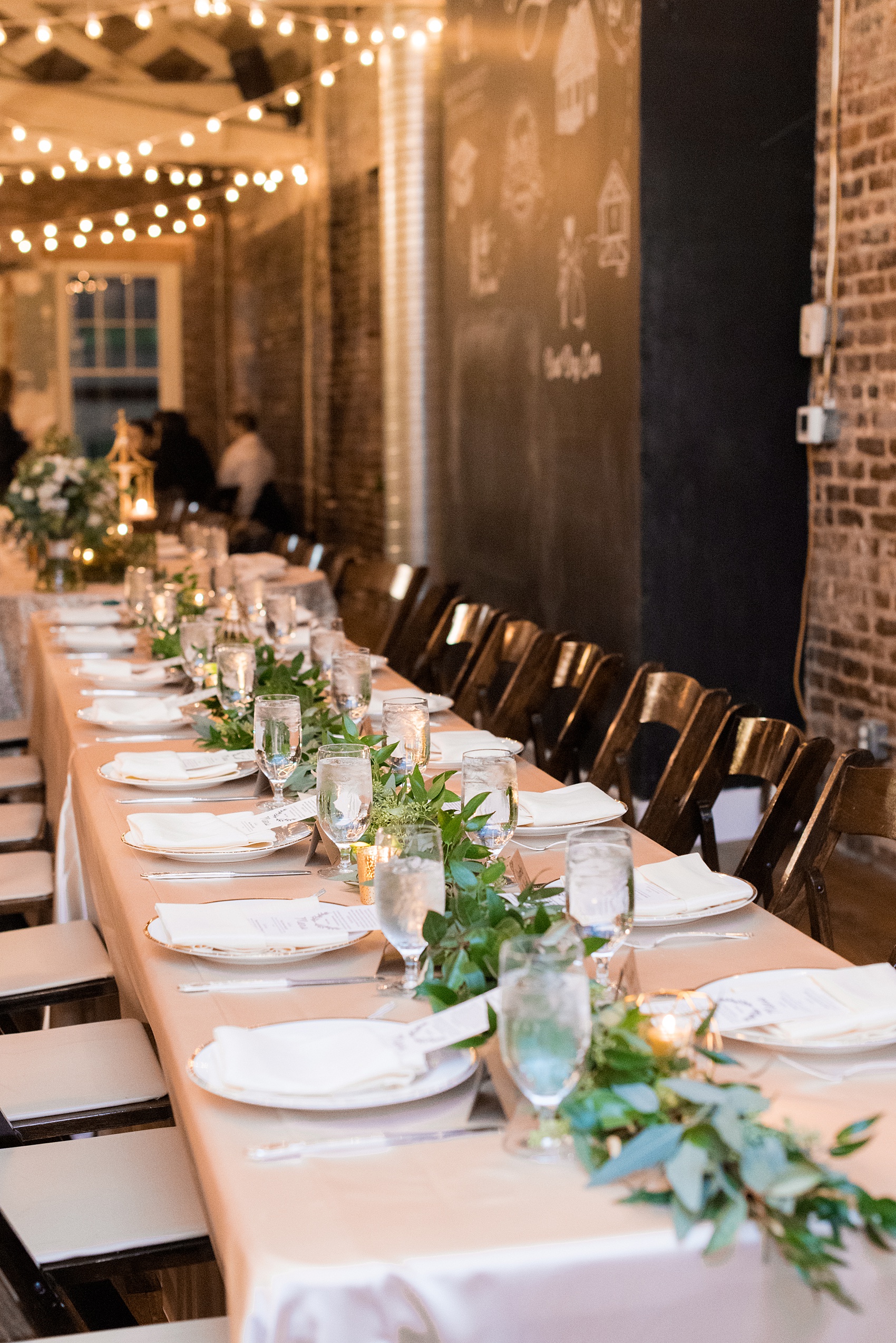 Pictures from a Christmas inspired wedding in downtown Raleigh, North Carolina by Mikkel Paige Photography. The bride and groom had a reception at the rustic venue, The Stockroom at 230, with pink linens, candlelight and greenery details. Click through for more ideas from their beautiful celebration with a pink and gold palette! #mikkelpaige #raleighweddingphotographer #downtownRaleigh #holidaywedding #ChristmasWedding #headtabledetails