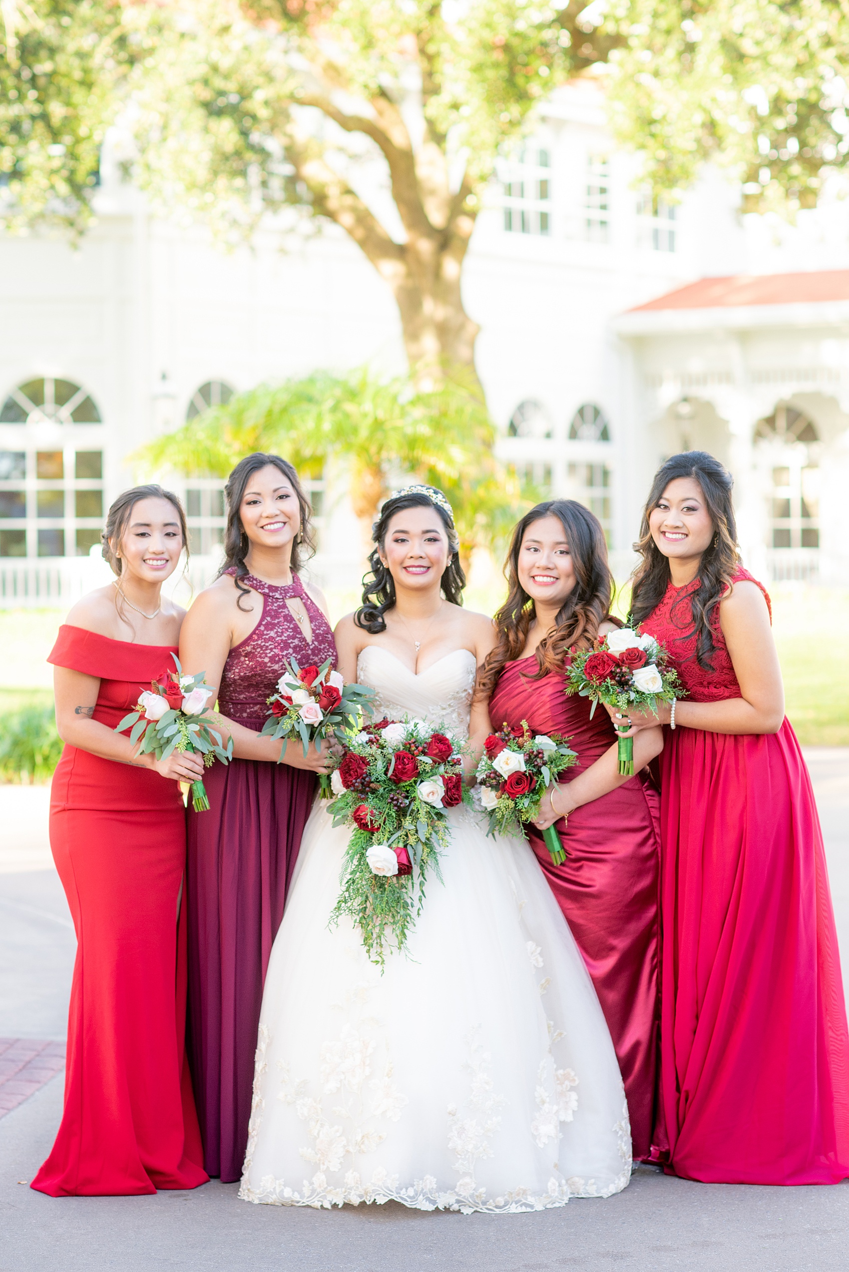 Photographs of a Walt Disney World bridal party by Mikkel Paige Photography. The bride chose the venues of the Grand Floridian, Wedding Pavilion and The Contemporary Resort for photos and fun locations. One even overlooked the Magic Kingdom Park! Their dream wedding included red details: the bridesmaids wore mismatched dresses and carried rose bouquets. #disneywedding #disneybride #waltdisneyworld #DisneyWorldWedding #BeautyandtheBeast #redrosewedding